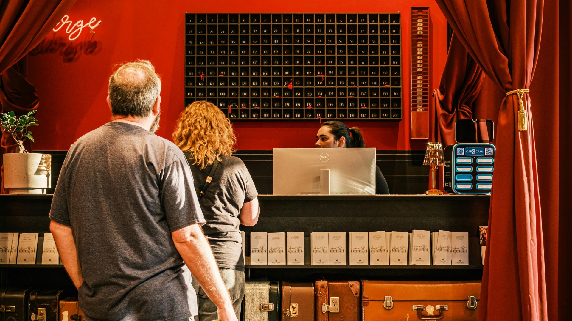 A couple with a dog checks in at a stylish, vintage hotel front desk.