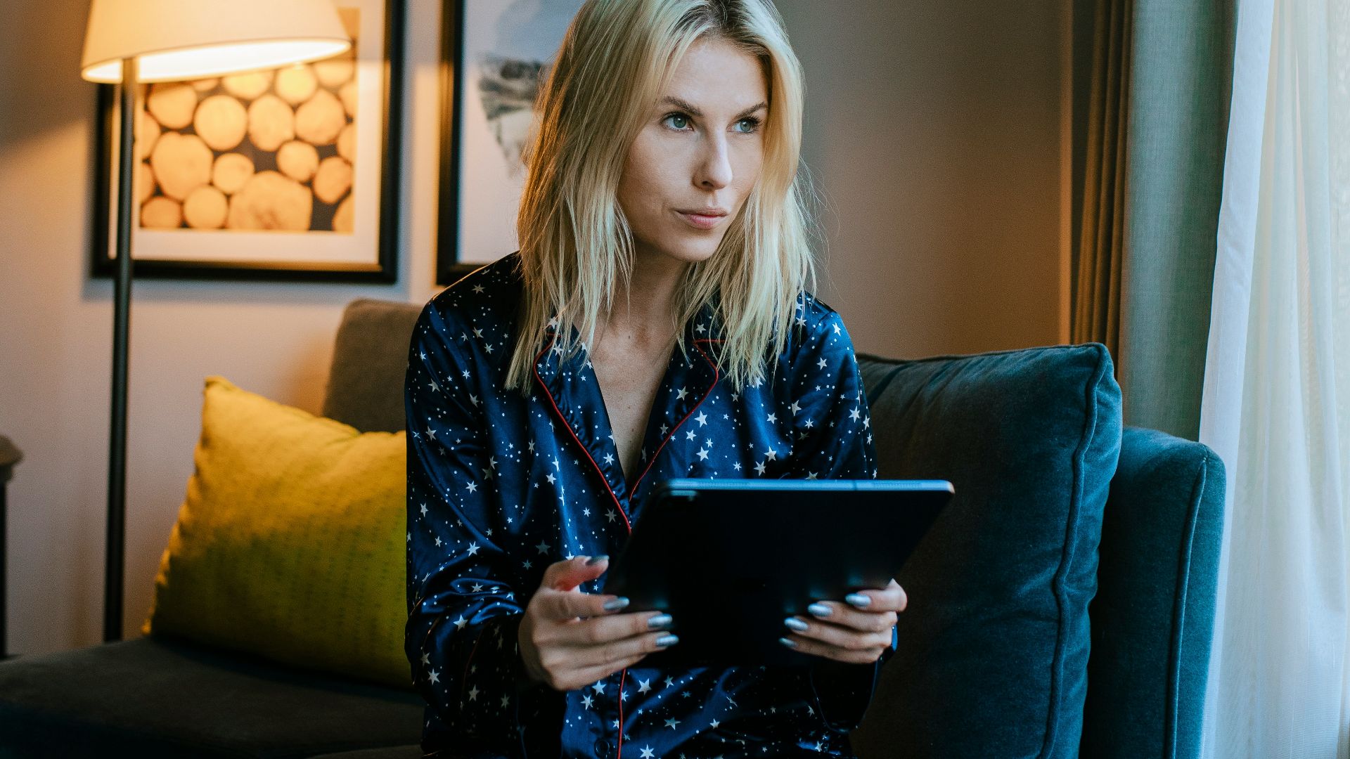 a woman sitting on a couch looking at a tablet