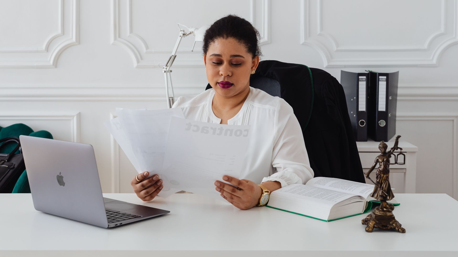 Confident businesswoman analyzing contracts at her clean, organized desk.