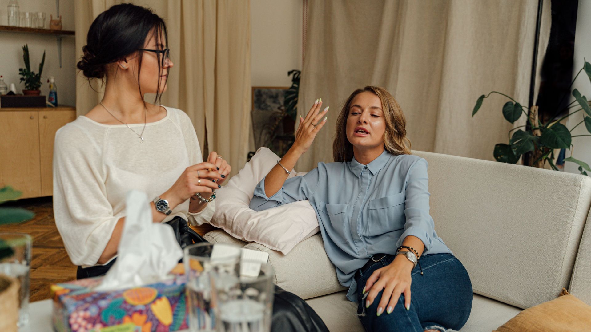 A counseling session with two women engaged in conversation on a comfortable sofa.