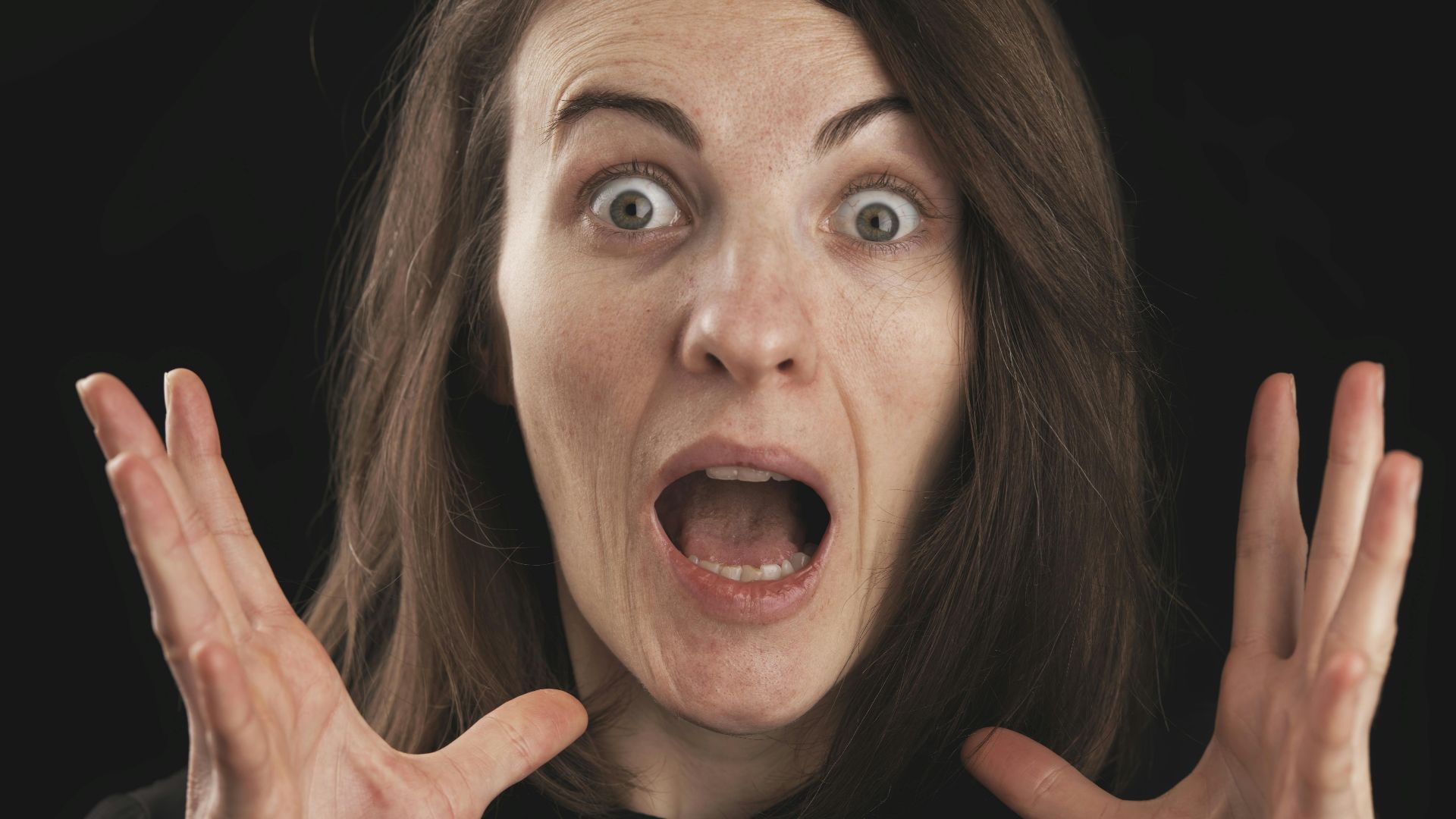 Close-up of a woman expressing shock and surprise with wide eyes and open mouth.