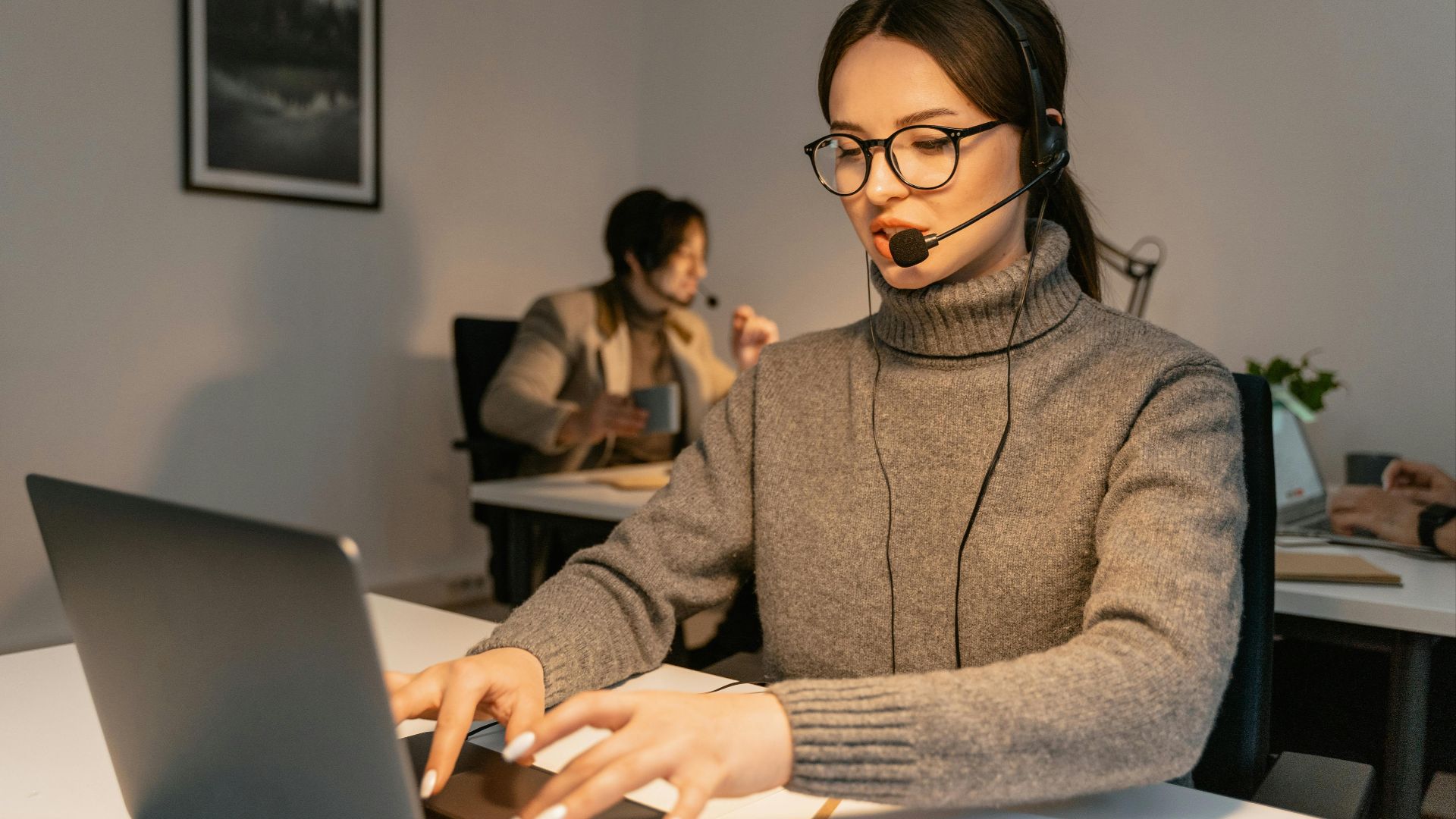 Two call center agents providing customer service in a modern office environment.