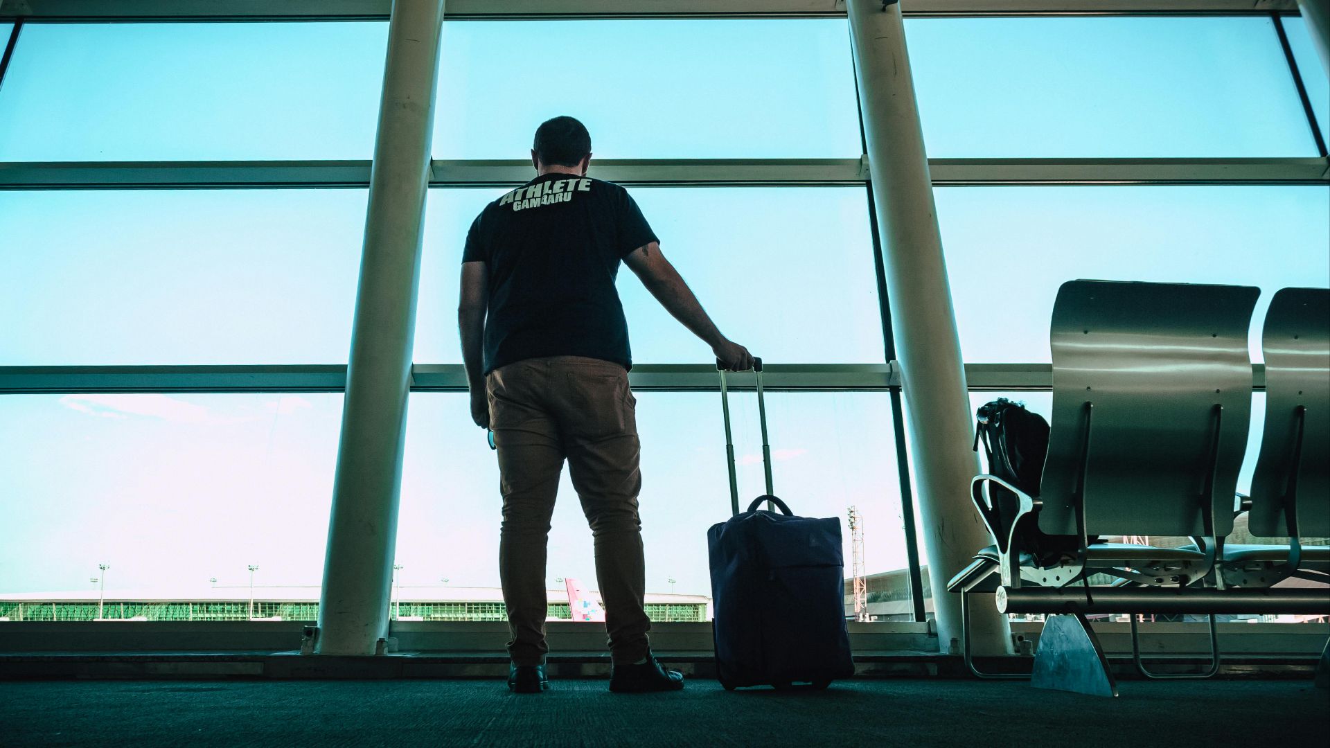 Man with luggage waiting at airport lounge, anticipating departure in a modern setting.