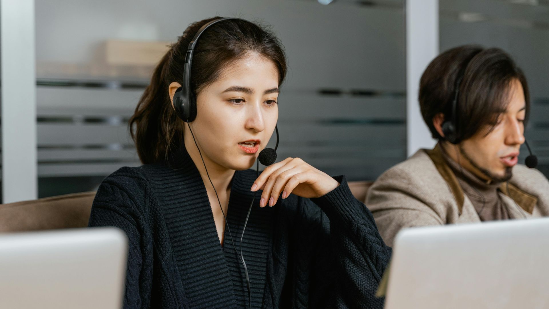 Two call center agents providing customer support in a modern office setting.
