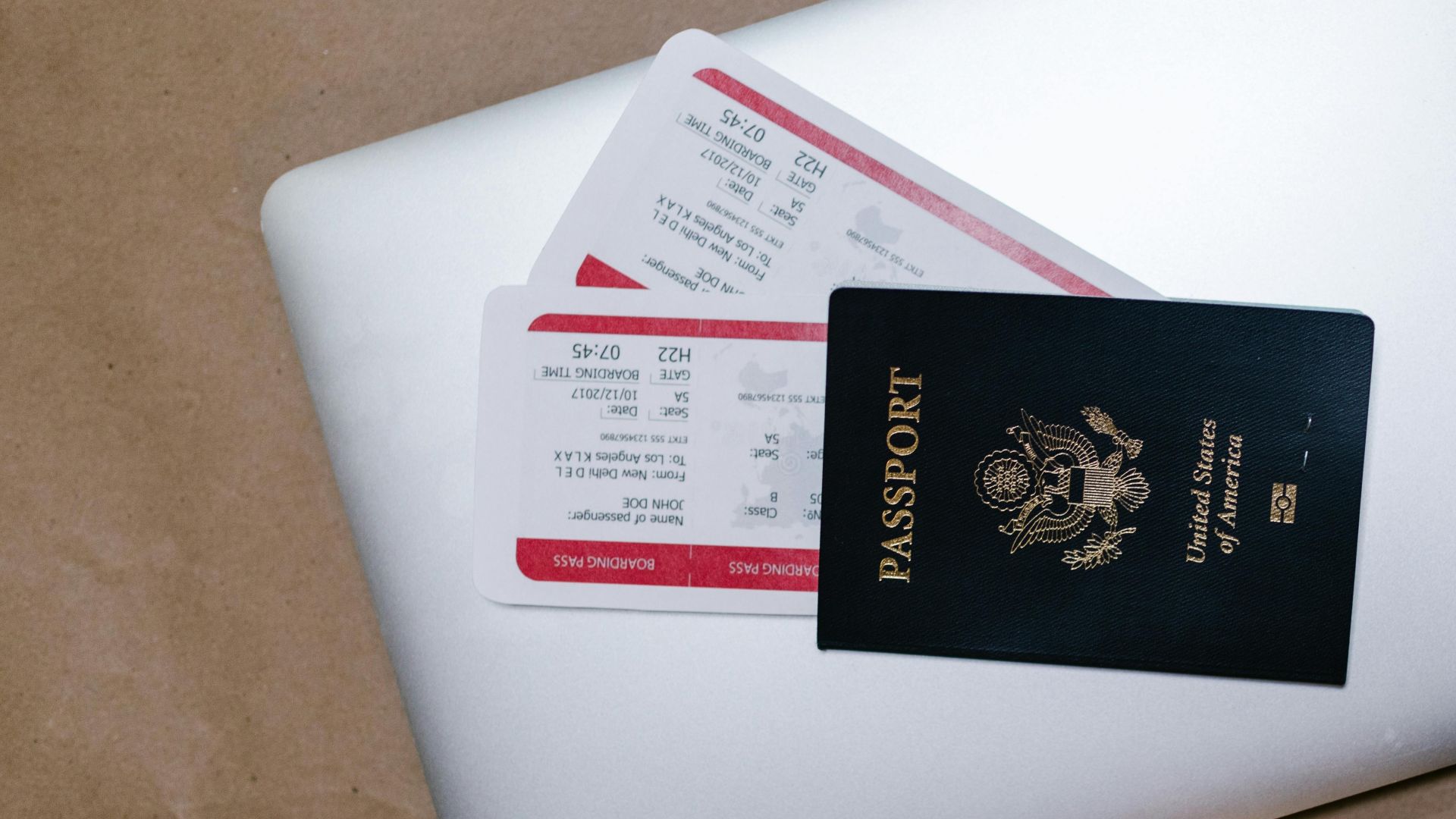 Close-up of a passport and boarding passes on a laptop, symbolizing travel preparation.
