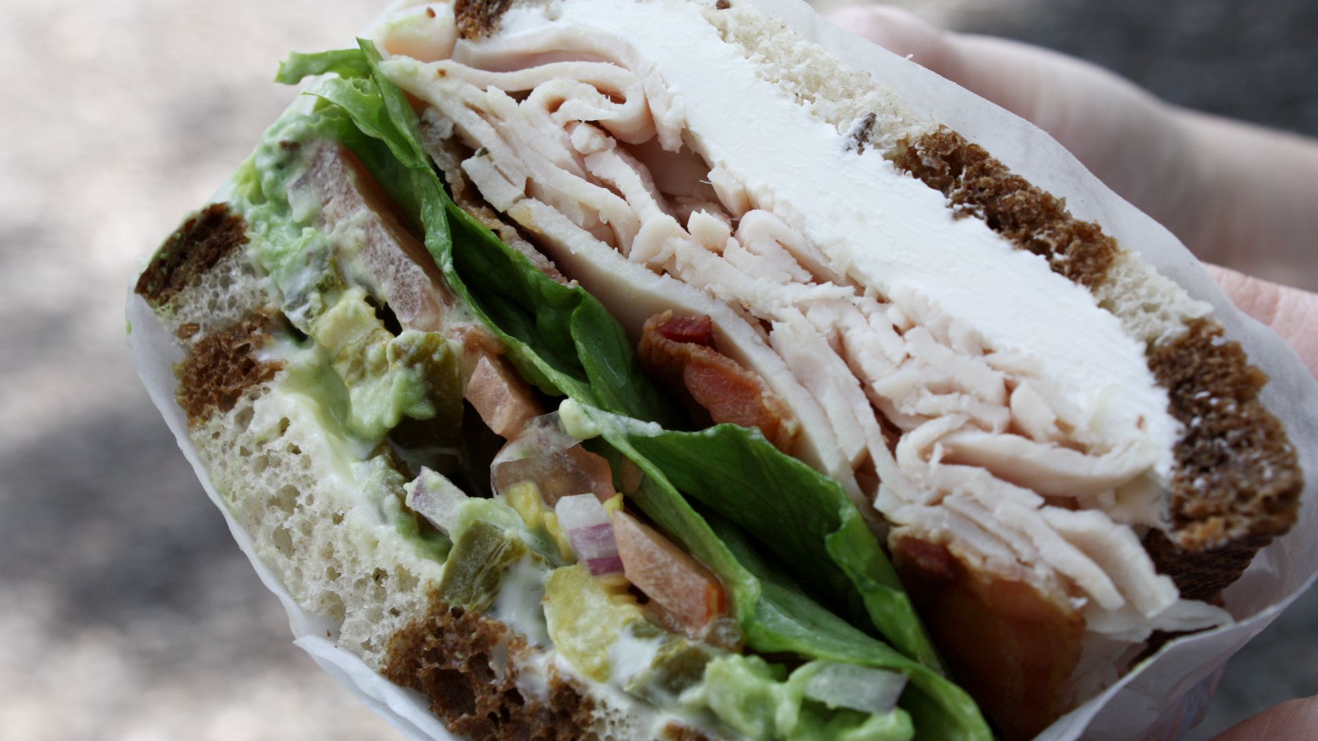Cream cheese, turkey, bacon, avocado, lettuce, tomato, onion, peppers, mayo, and mustard on rye. From the Aroma Cafe in Oakland.