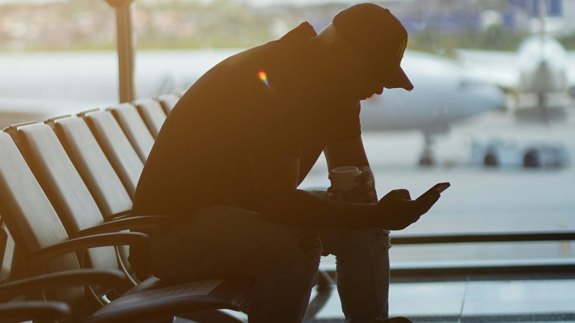 a man sitting at an airport looking at his cell phone