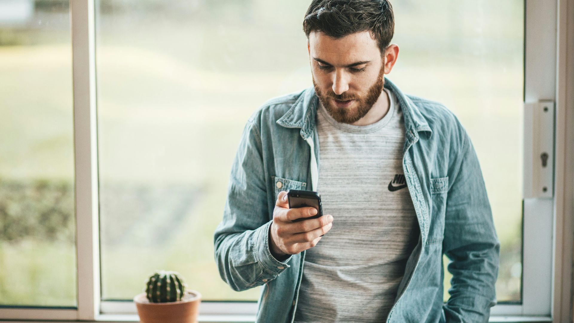 man holding a smartphone near the window