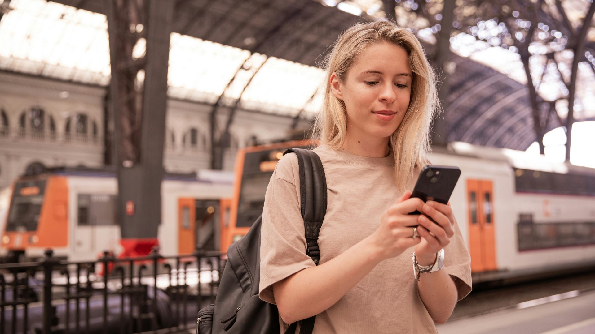 a woman standing in a train station looking at her cell phone