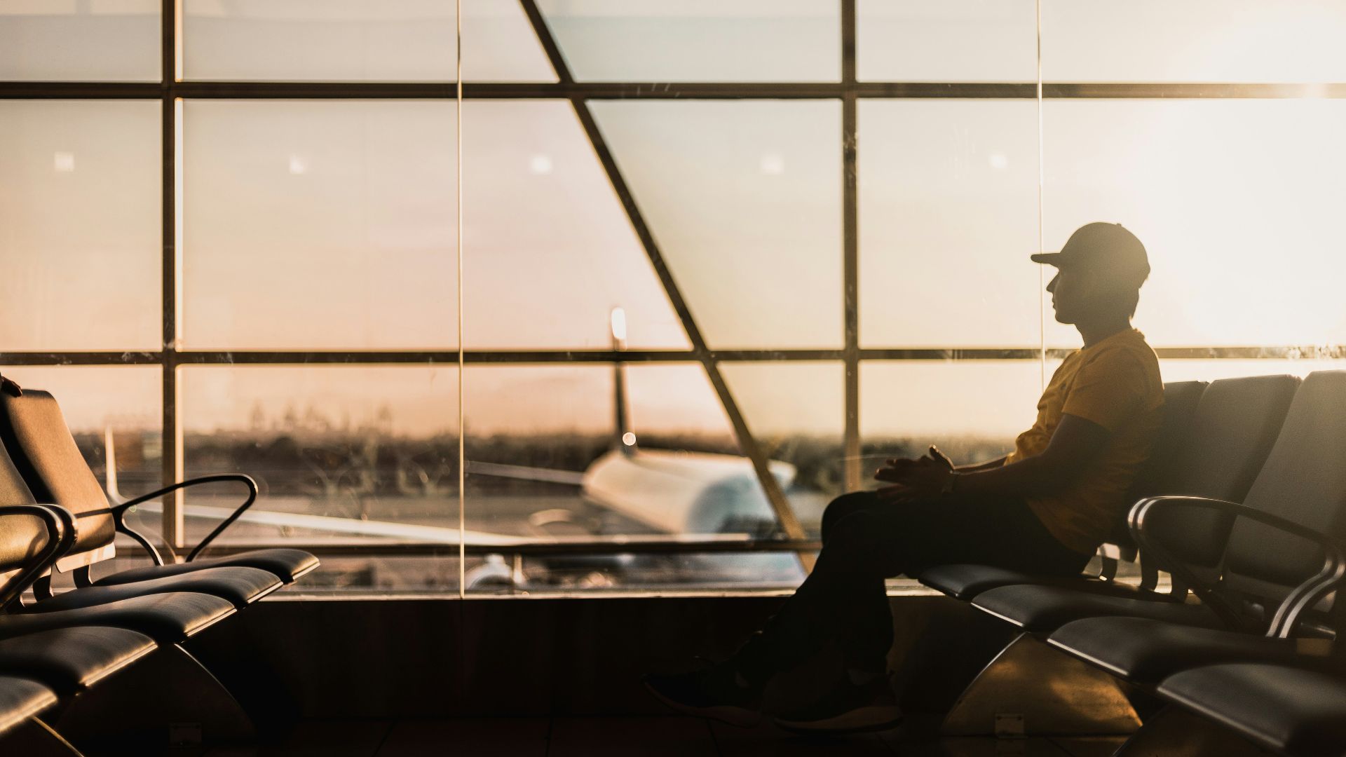 man sitting on gang chair near window