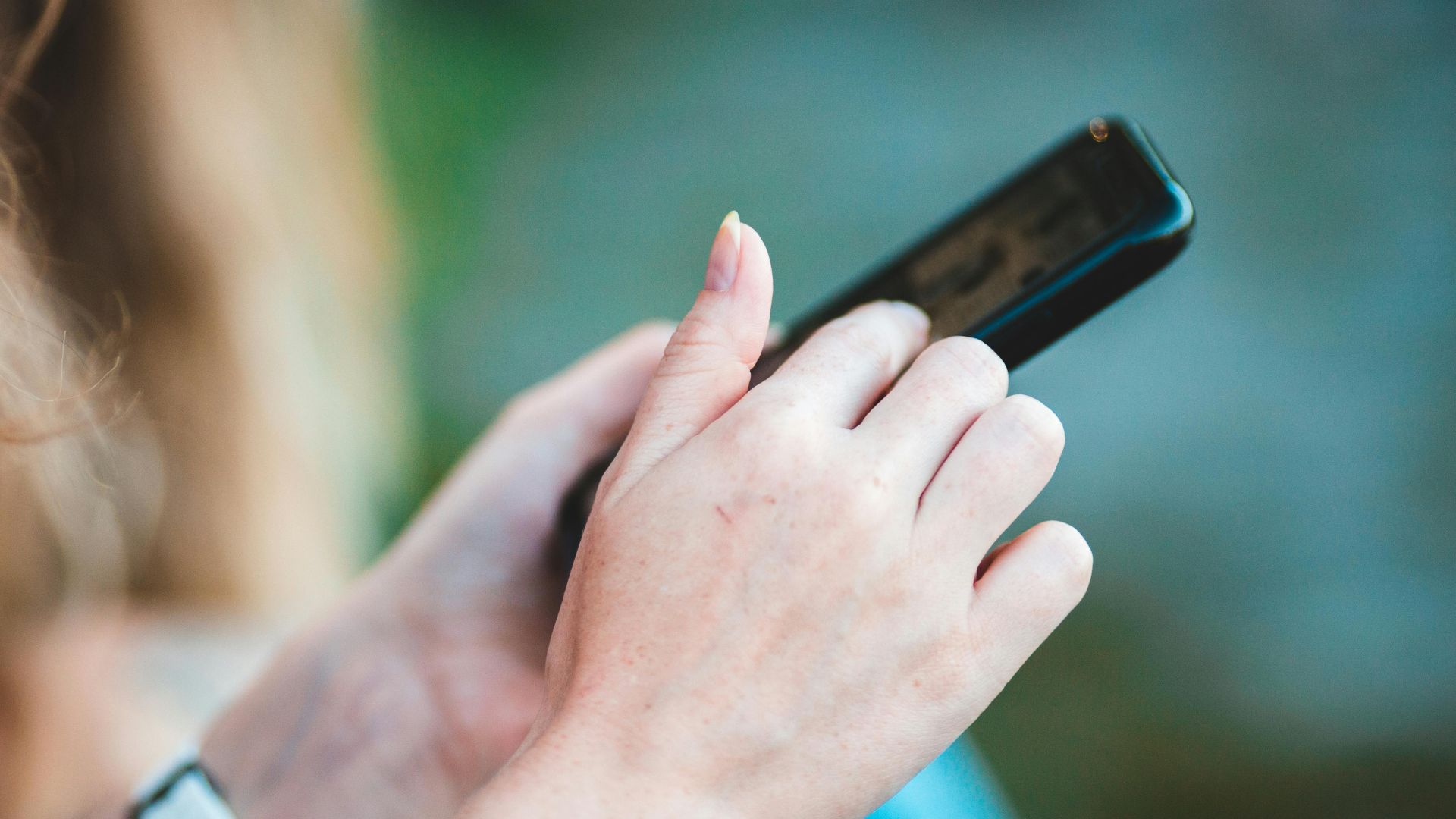 Hands holding a smartphone with blurred background, showcasing modern technology use.