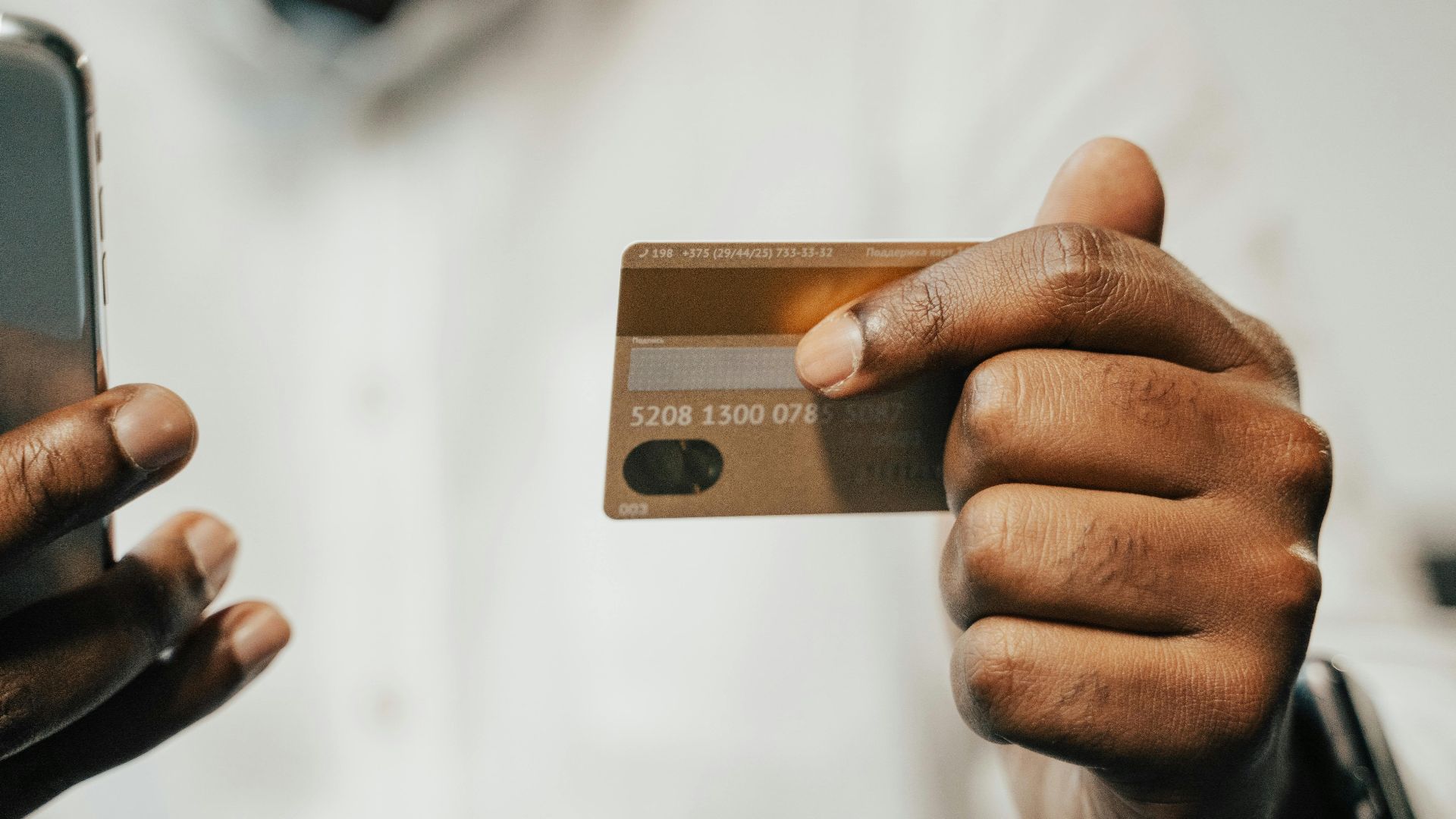 Person using a smartphone and credit card for online shopping or payment.