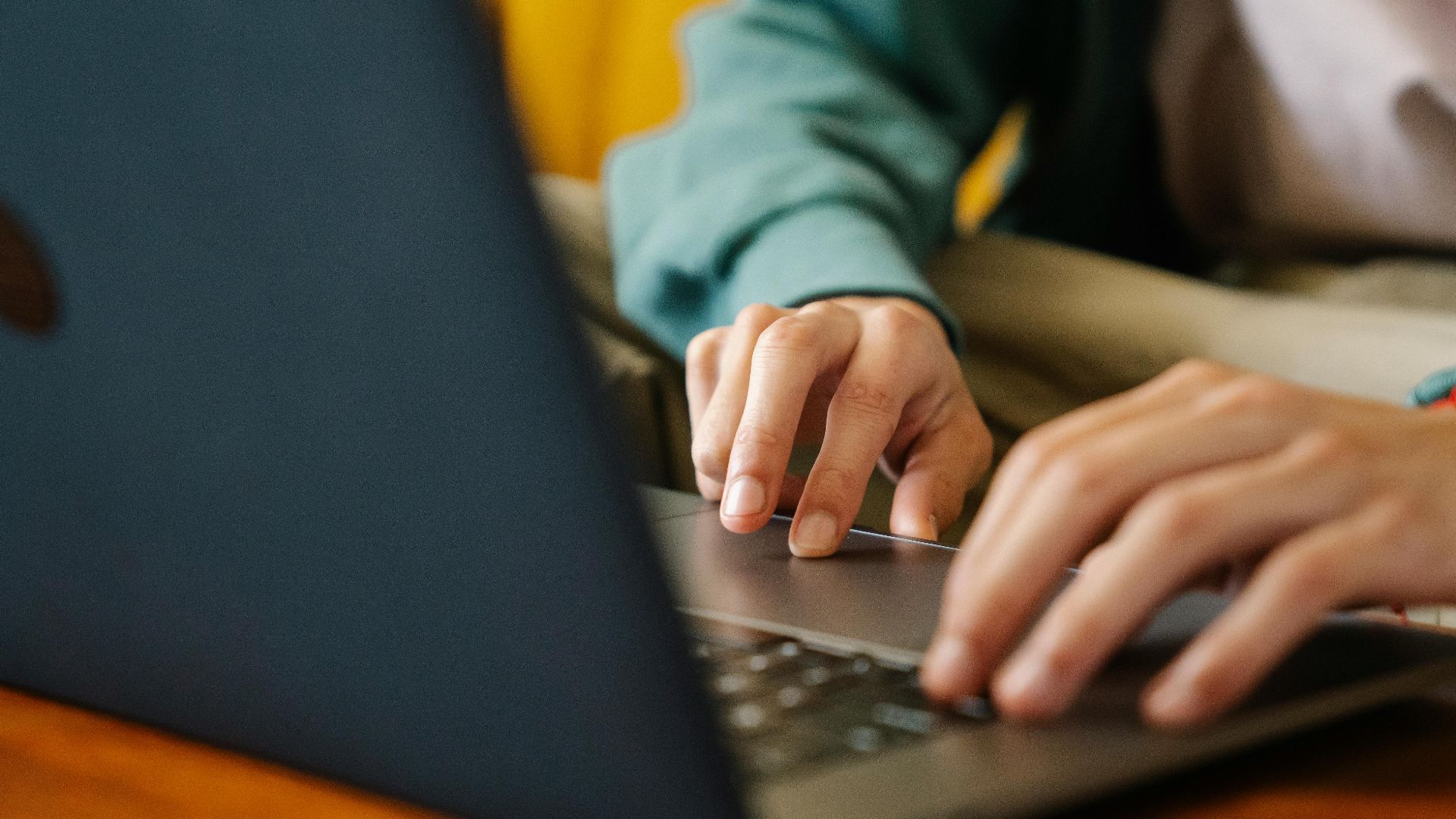 Crop unrecognizable distance employee surfing internet on netbook while working on project at desk in room
