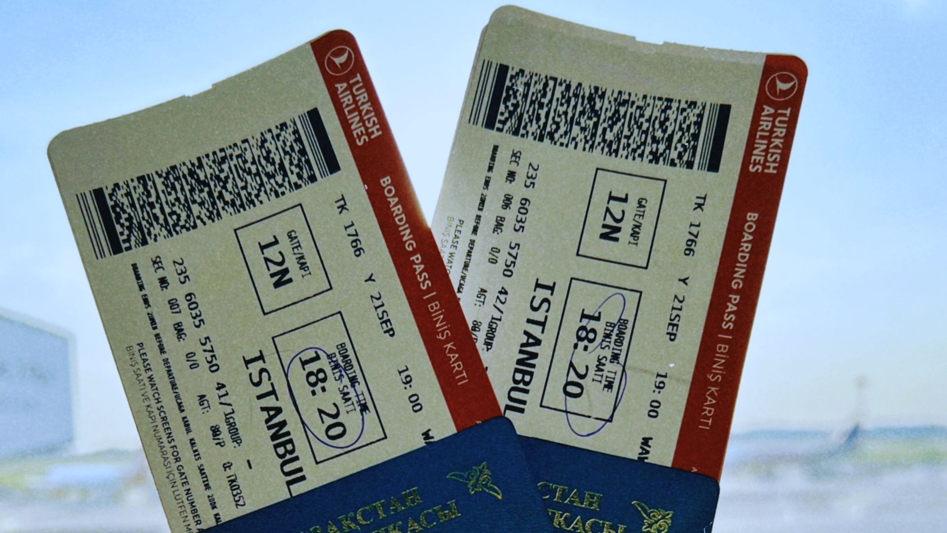 A Kazakhstan passport holds two airline tickets against an airport backdrop in Warsaw, Poland.
