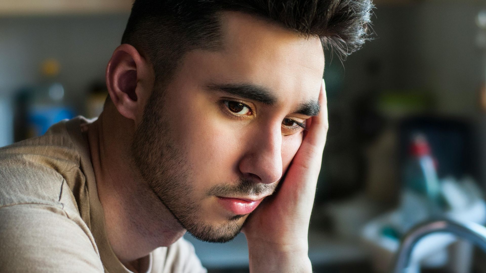 Portrait of a thoughtful young man in casual wear, indoors with soft lighting.