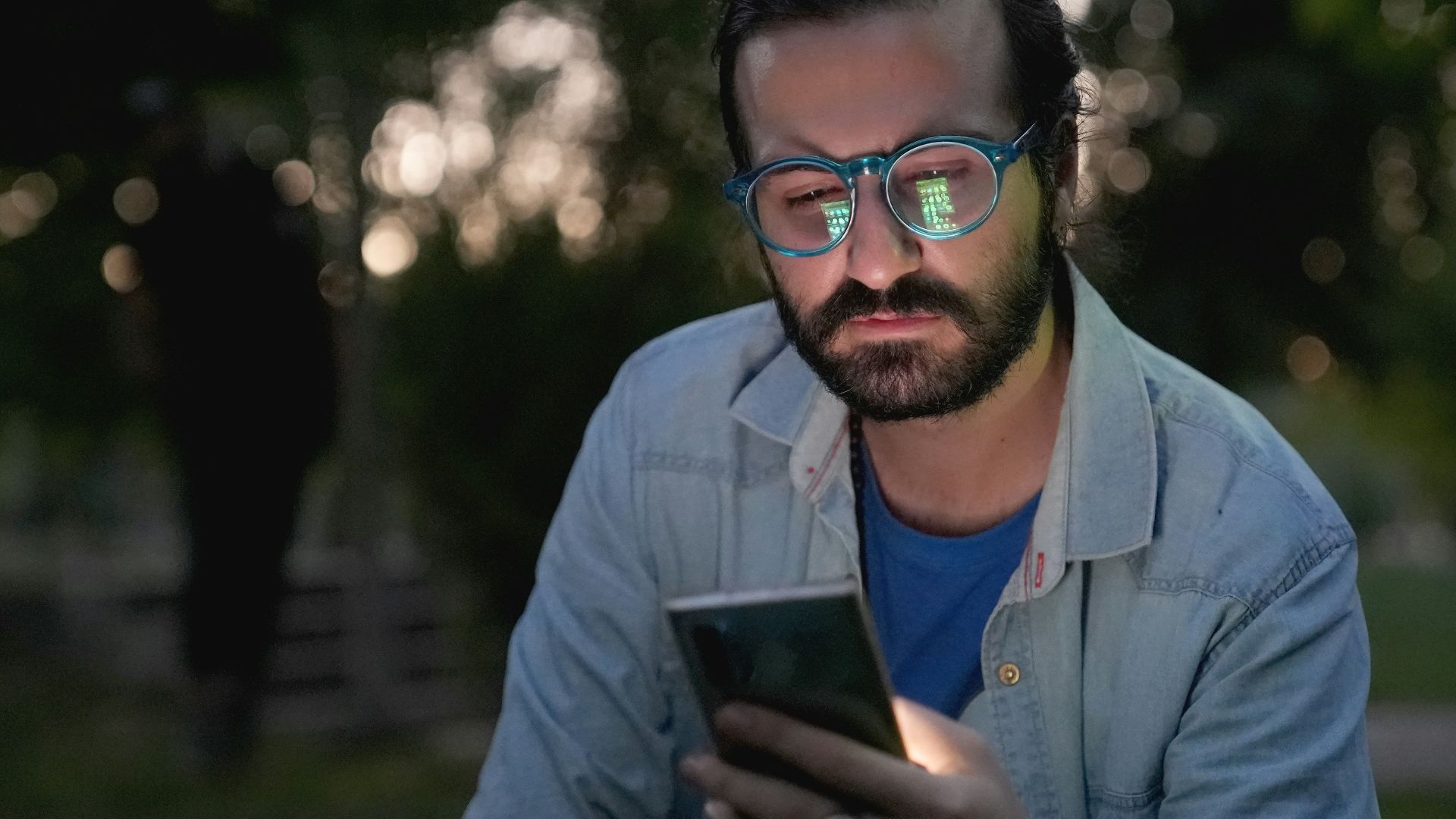 a man with glasses looking at a cell phone