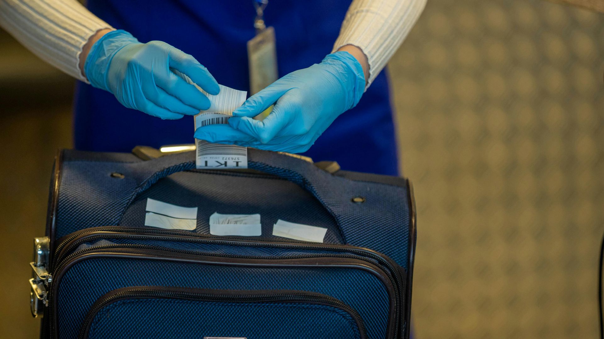Close-up of airport security process with gloved hands inspecting luggage tags.