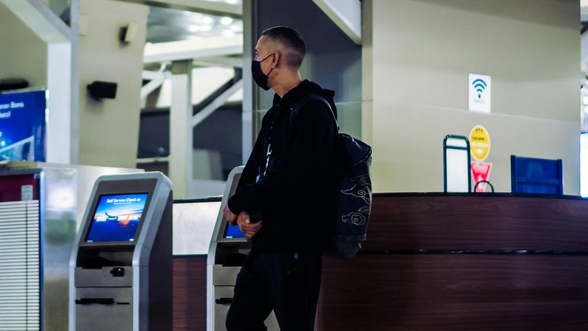 A man wearing a mask at an airport check-in counter during the pandemic.