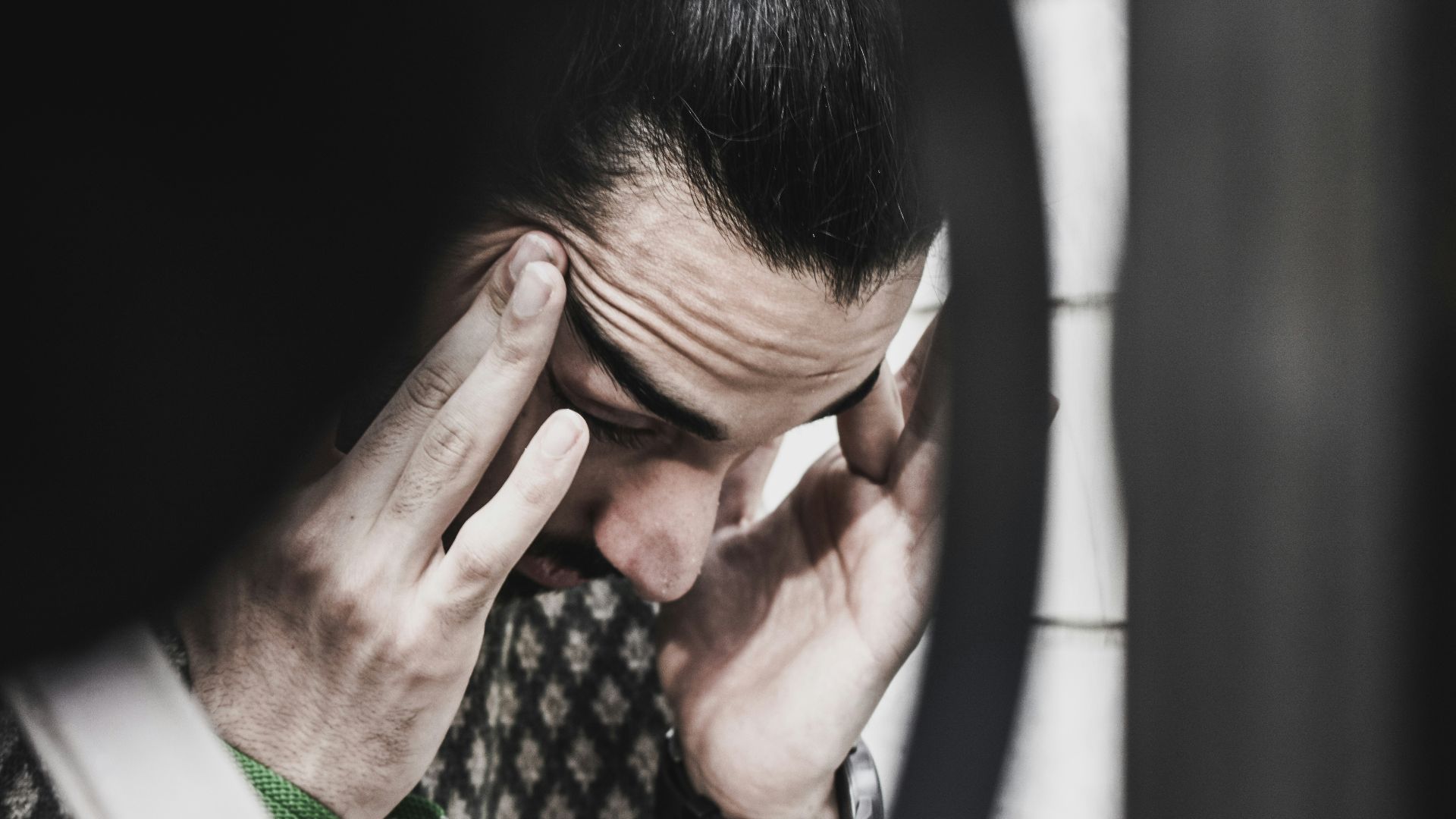 man holding his temples and looking down