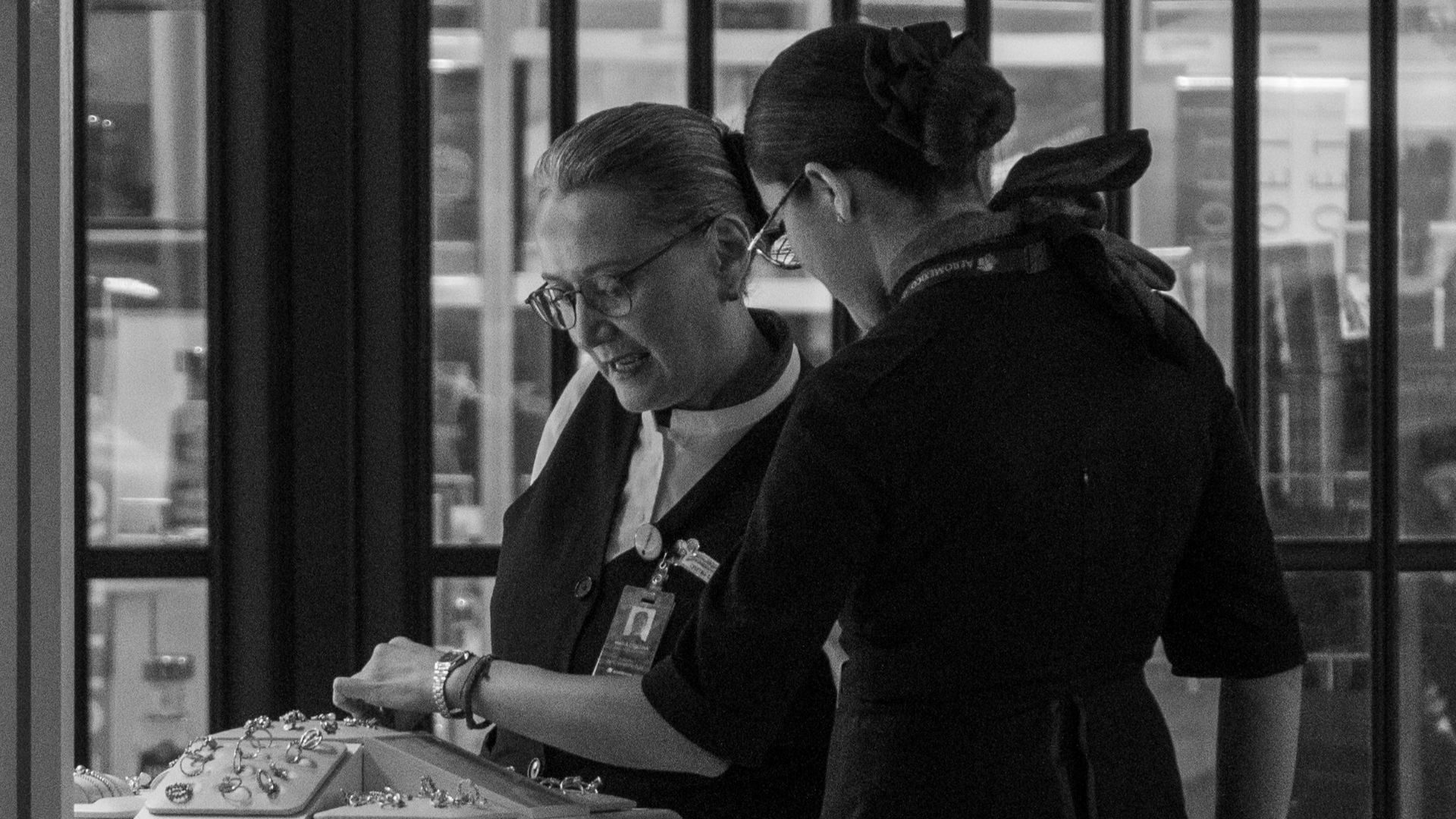 Two airline staff members working at a terminal counter, assisting passengers.