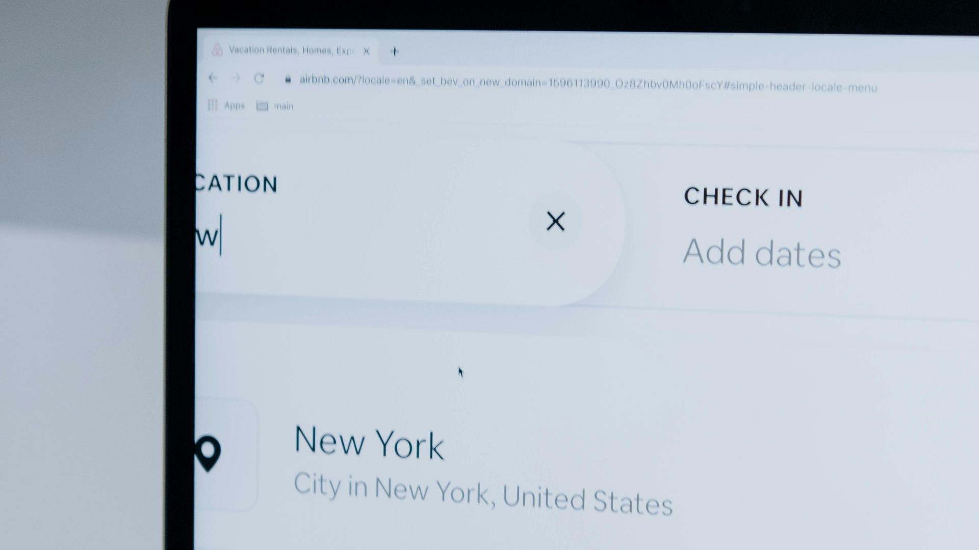 Hands typing on a laptop near New York location search screen.