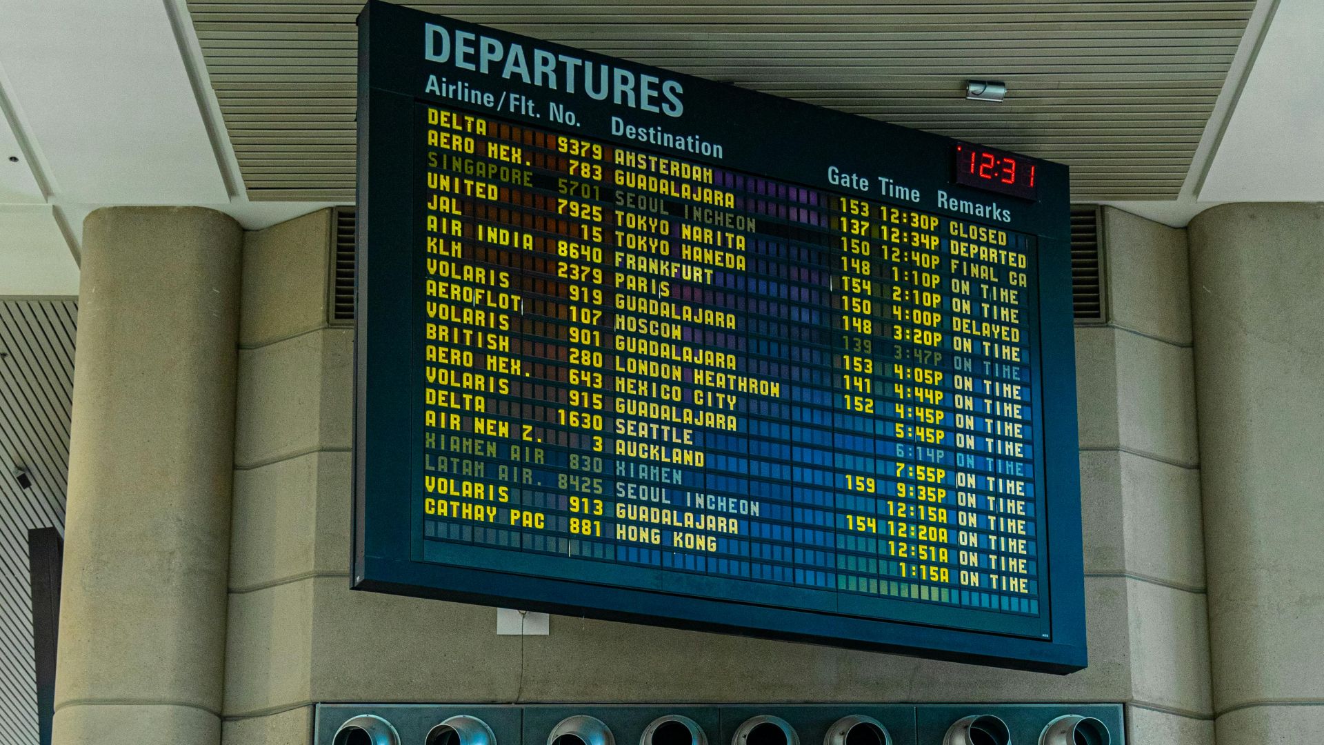 Digital departure board and airline check-in counters inside a modern airport terminal.