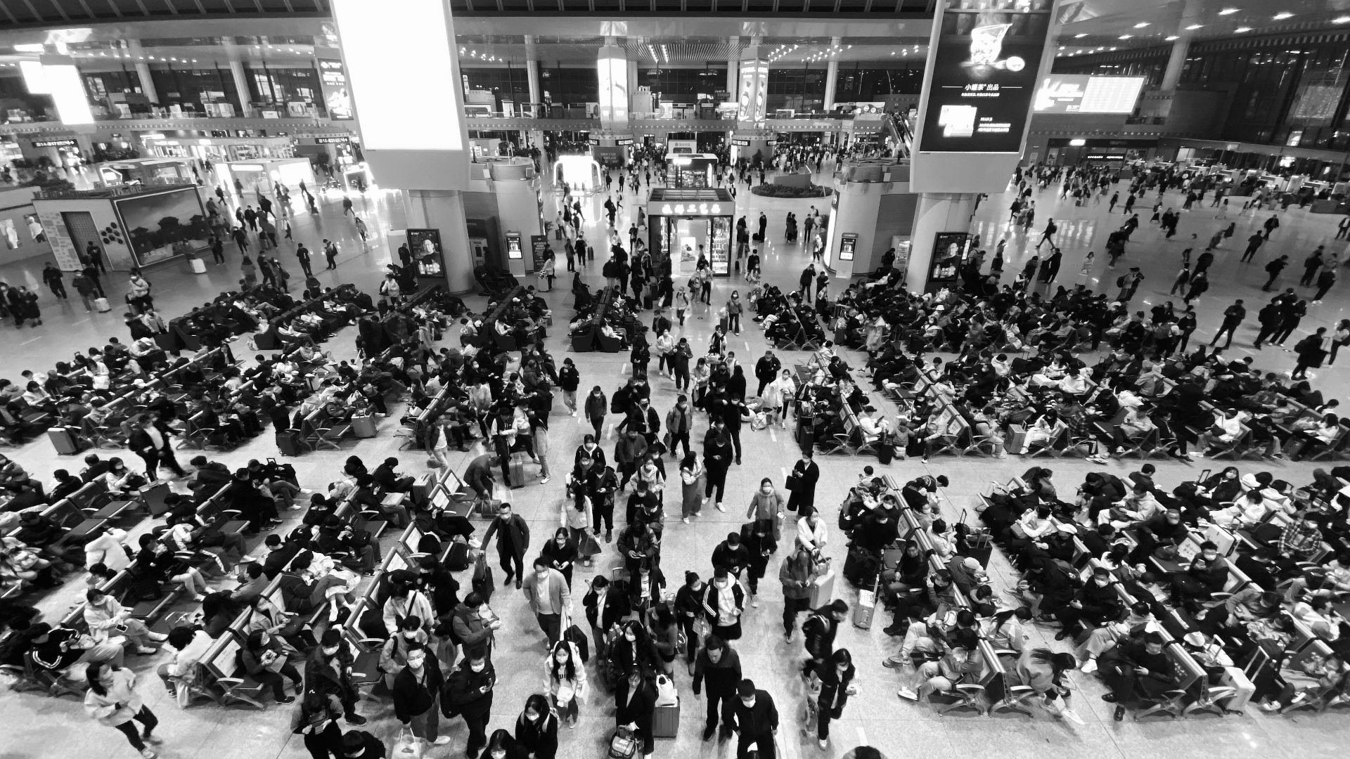 Crowd of people walking and sitting in a bustling airport terminal, high angle view.