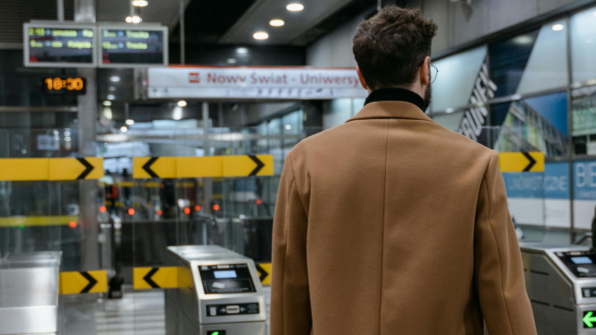 Businessman holding briefcase walking through metro station gates in urban setting.
