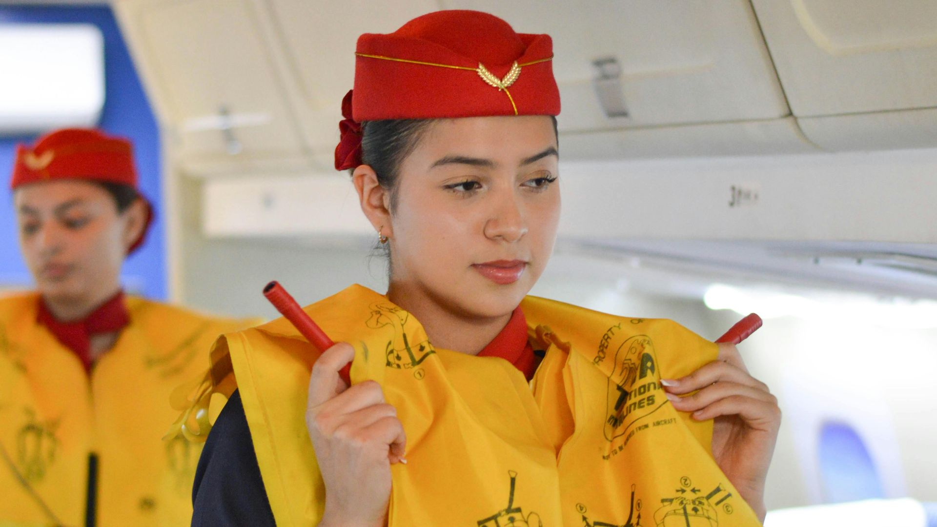 Airline flight attendants conduct a safety demonstration inside the aircraft cabin.