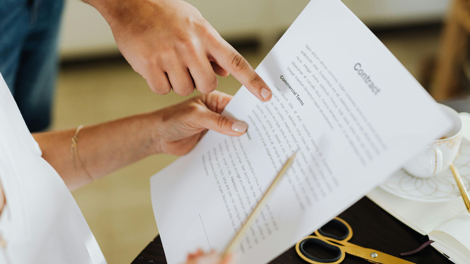 Close-up of two people discussing a business contract at a desk in an office setting.