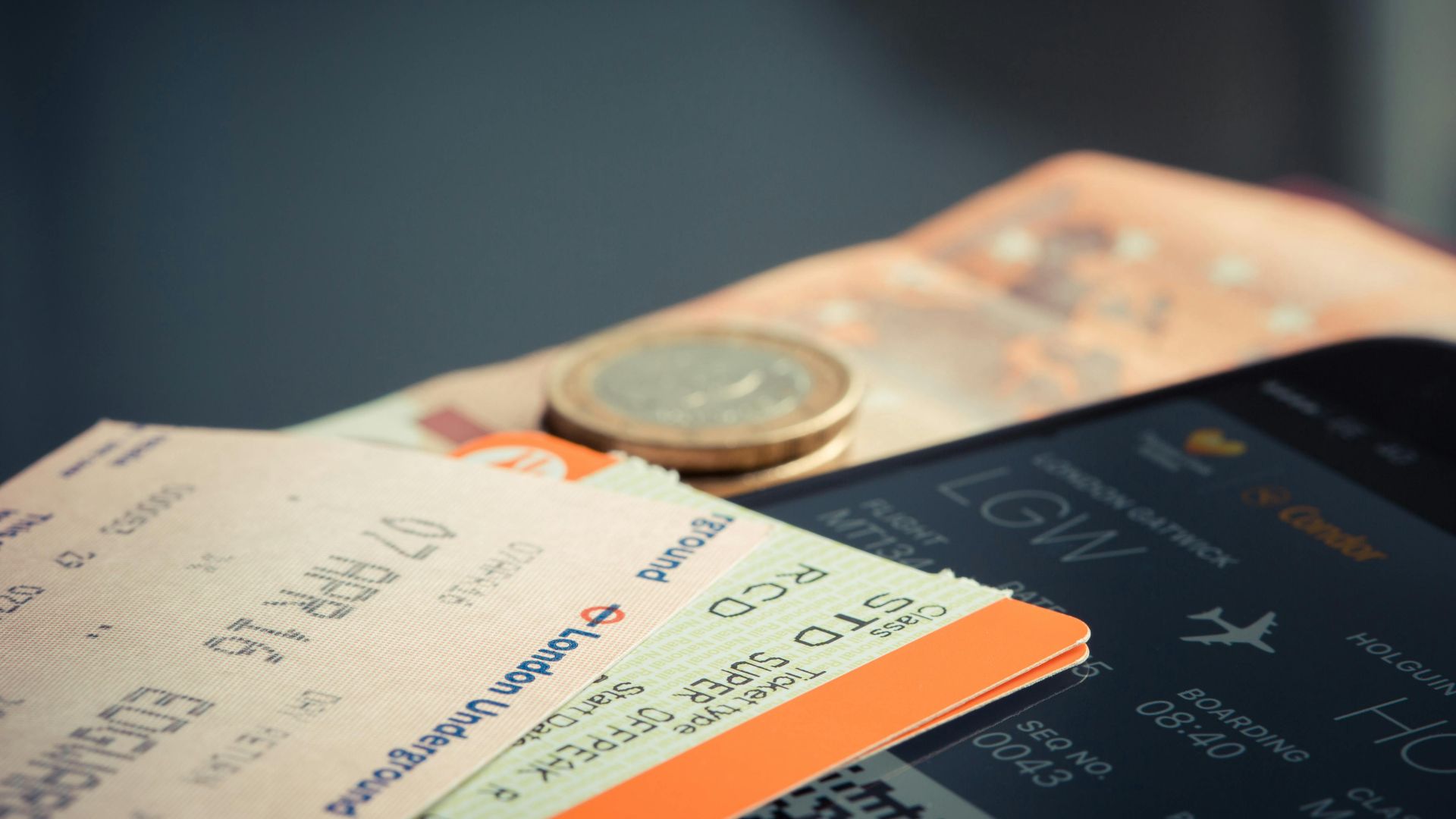Airline ticket with euro coins and smartphone displaying flight details.