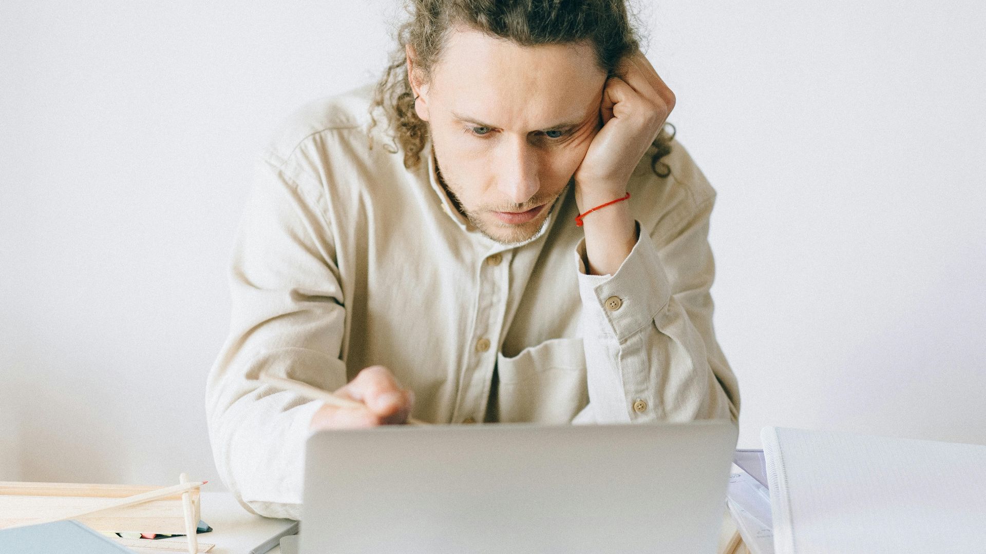 Adult man stressed at work, experiencing burnout while working on laptop at desk.