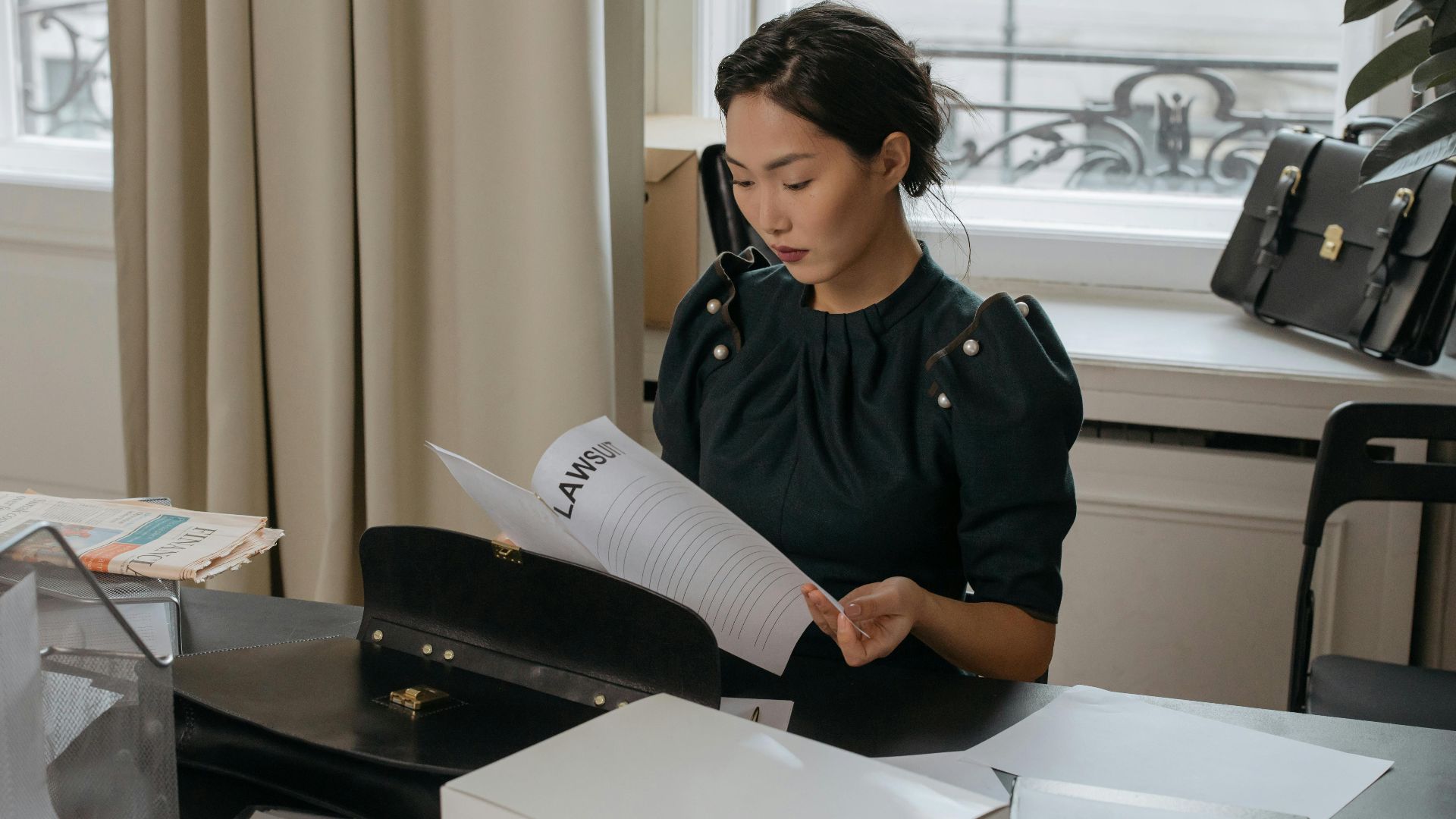 Elegant young woman reading documents in a stylish office setting.