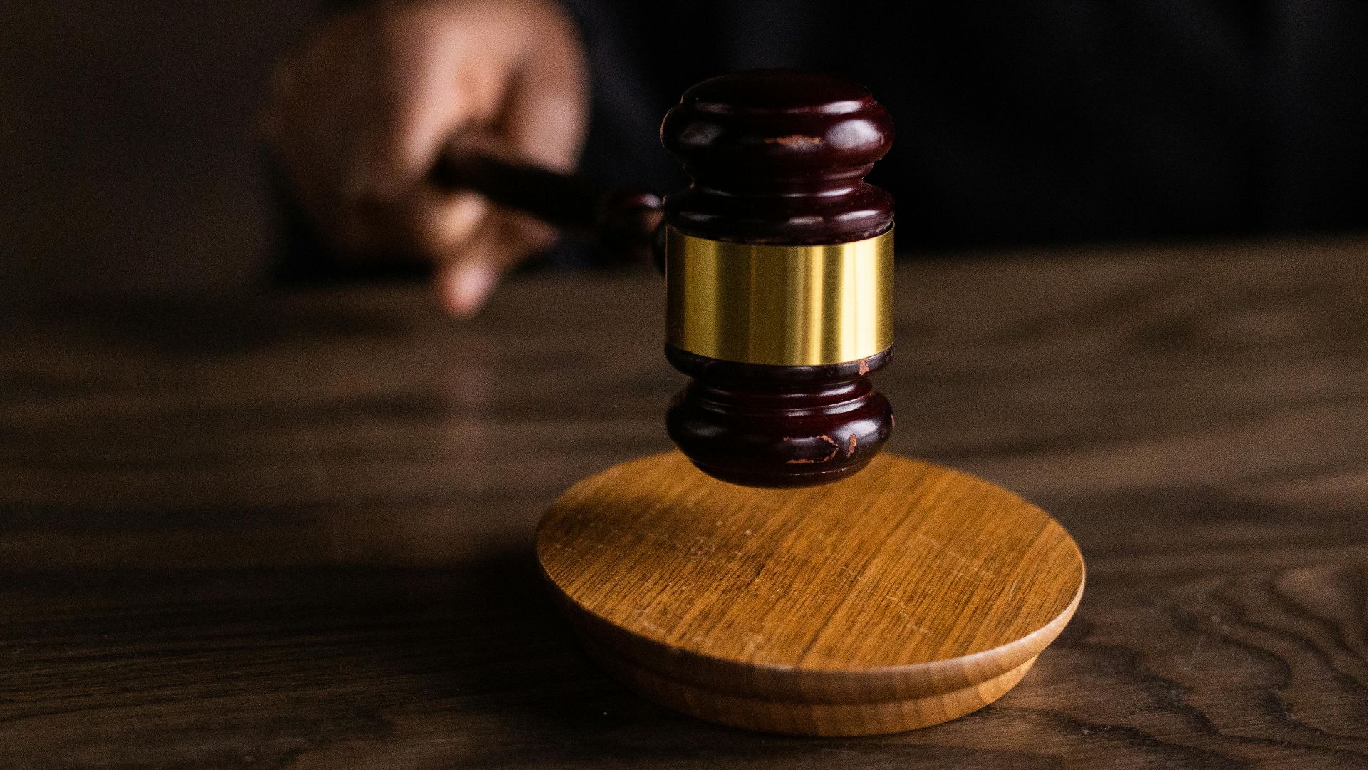 A gavel striking a sound block, symbolizing justice and legal authority in a courtroom setting.