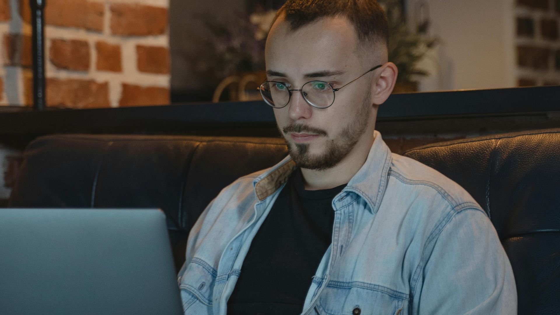 A man works on a laptop from a comfy couch in a stylish home setting.