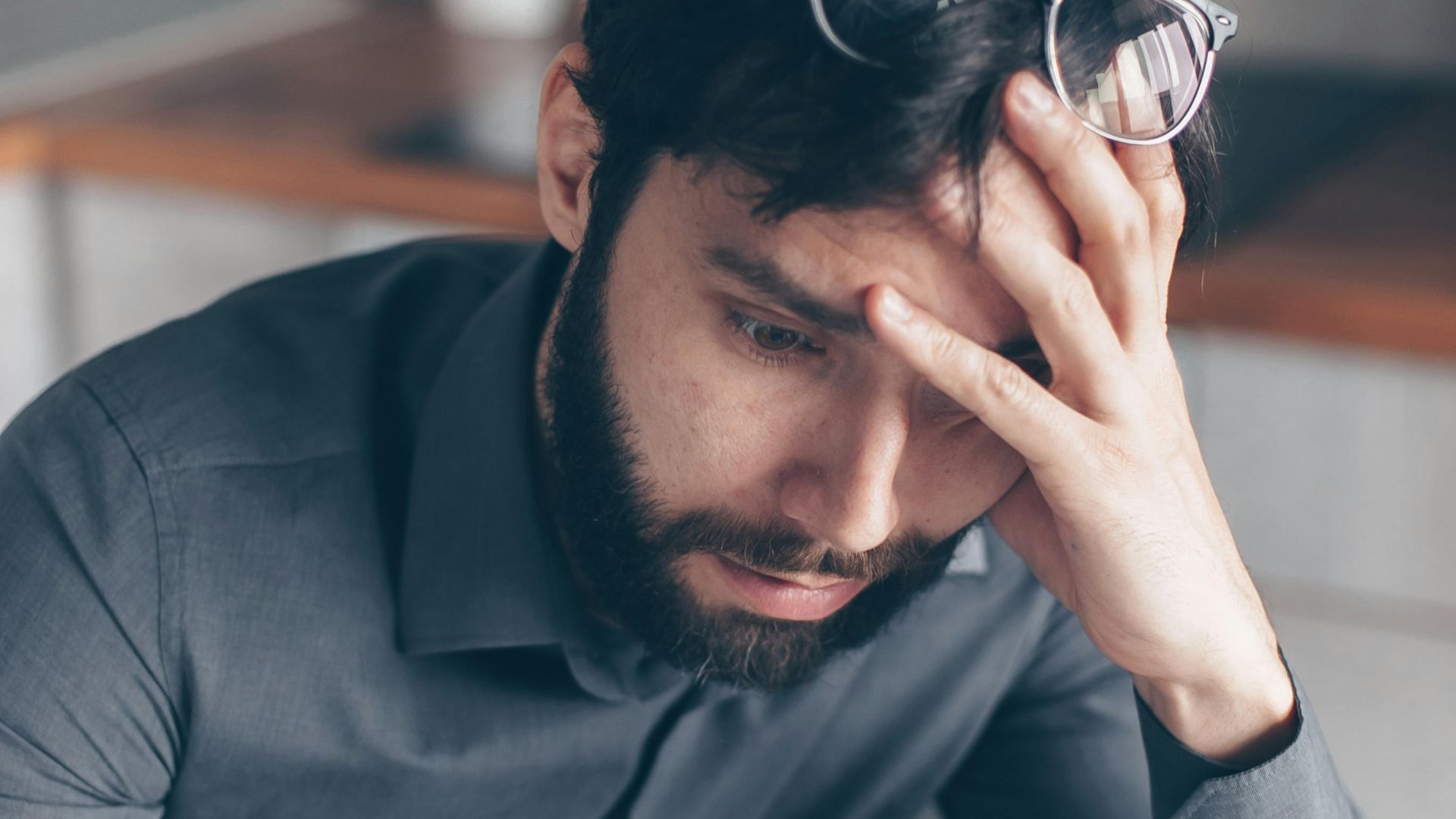 Man with eyeglasses on head looks worried as he reads paperwork, expressing concern.