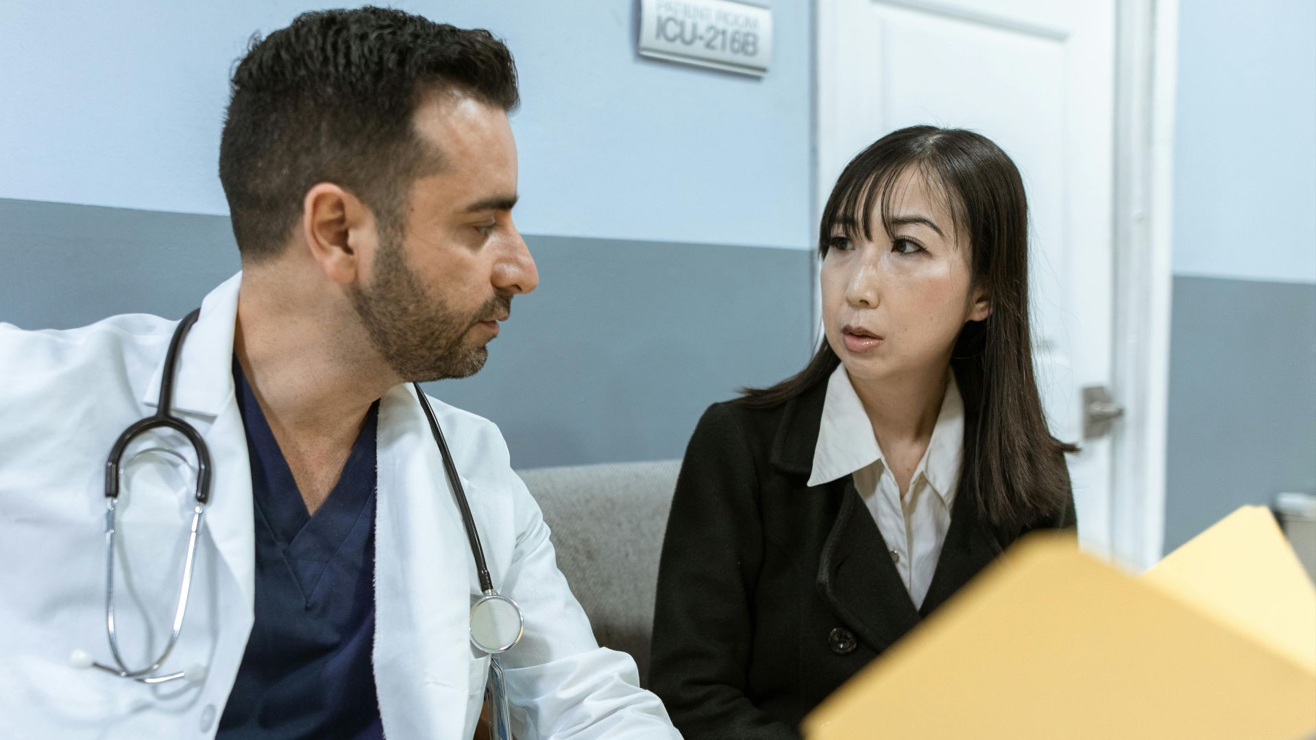 A doctor consults with a colleague in a hospital, examining medical documents.