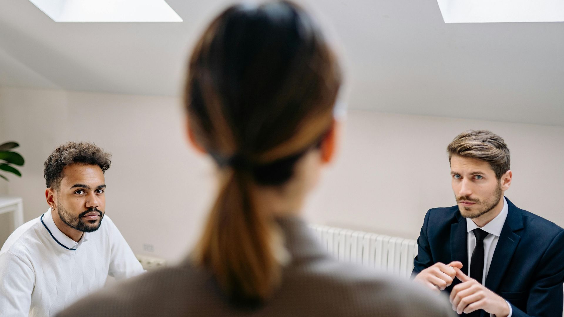 A professional business meeting involving three adults in a modern office setting.