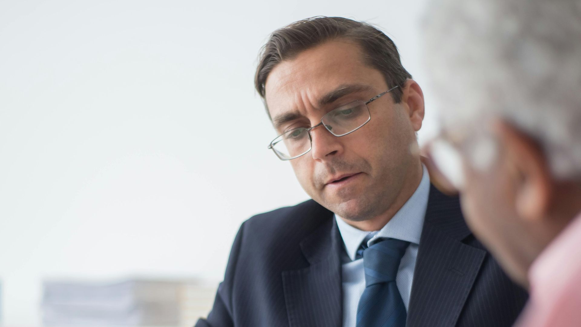 Senior man in discussion with consultant in office setting, reviewing documents.