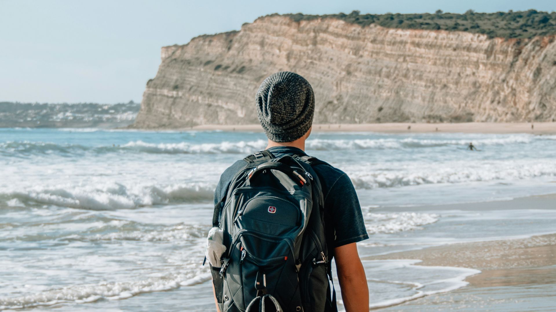 man walking on seashore near cliff