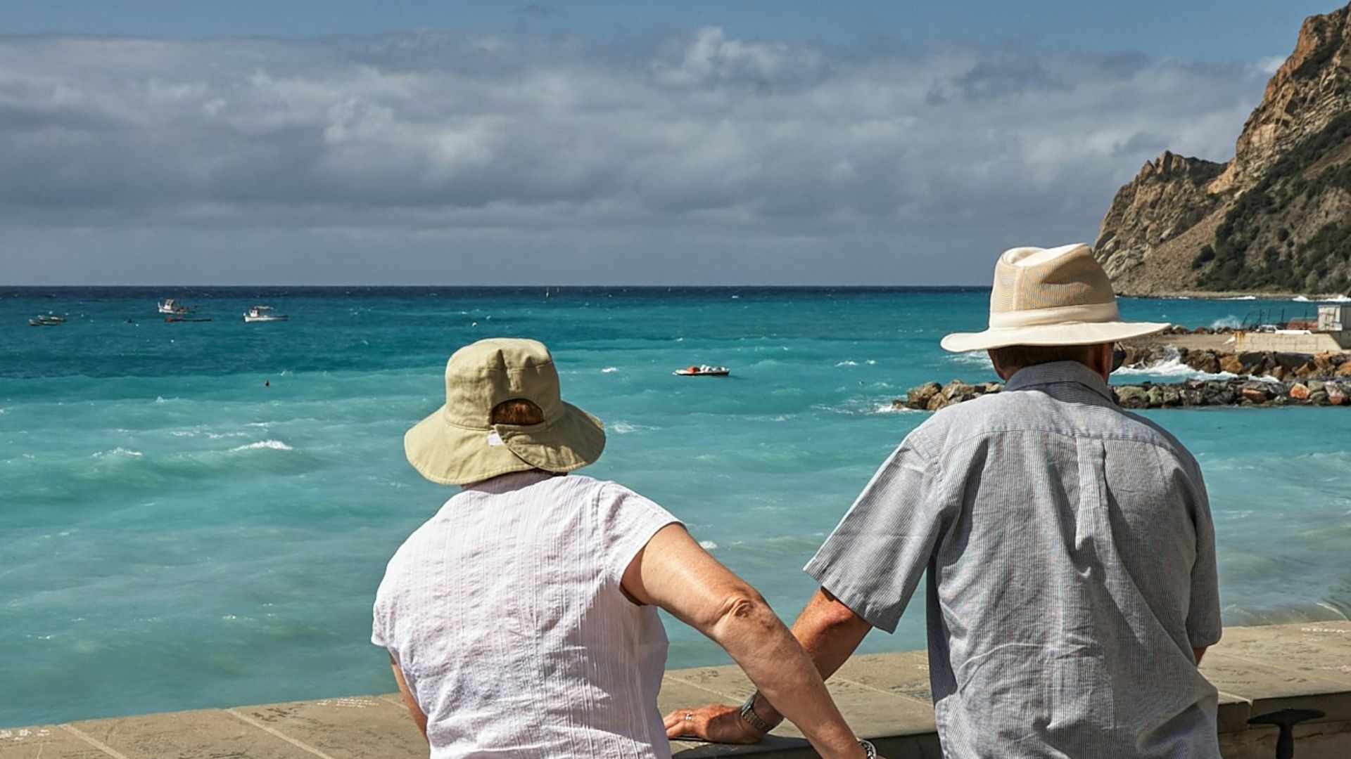 man and woman standing beside concrete seawall looking at beach