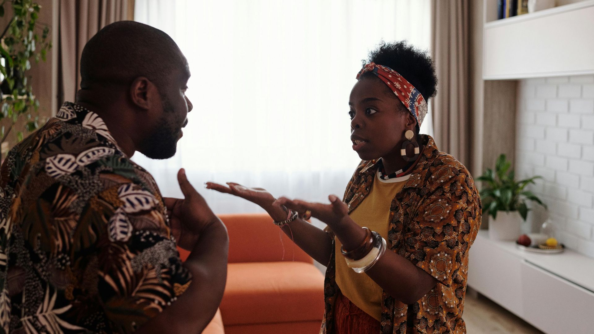 A couple arguing passionately in their living room, expressing emotions and gestures.