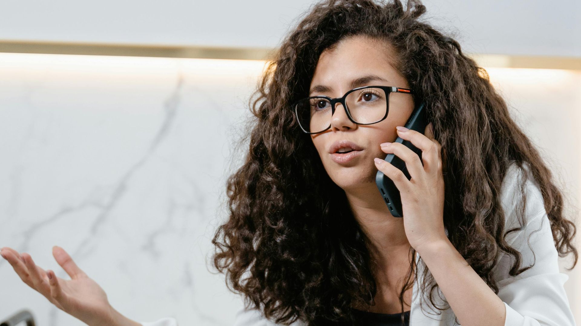 An adult woman discussing on the phone in a stylish modern kitchen setting.