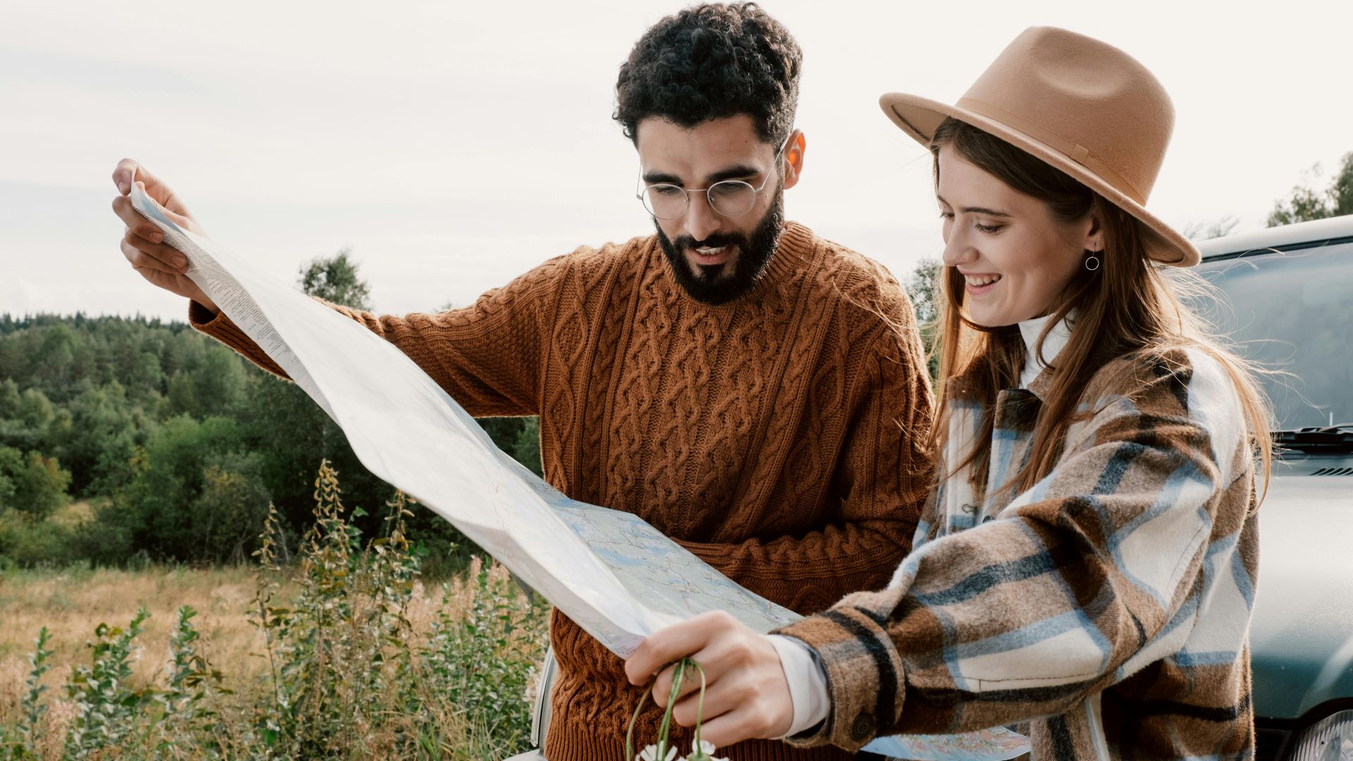 A couple in cozy attire examining a map for their outdoor adventure.