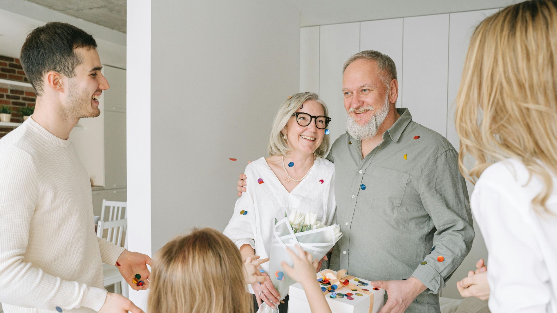 A joyful family gathering with gifts and confetti, celebrating togetherness and happiness indoors.