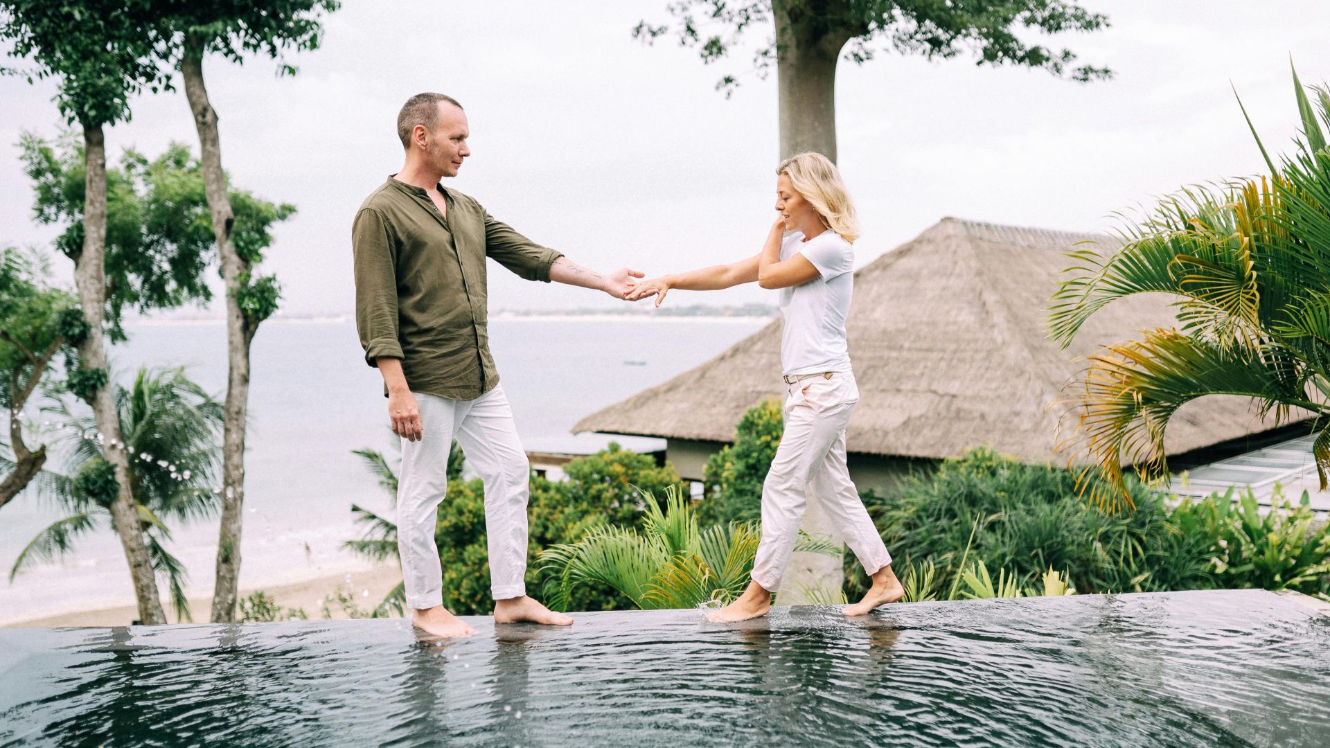 Couple holding hands and enjoying a tropical vacation by the poolside.
