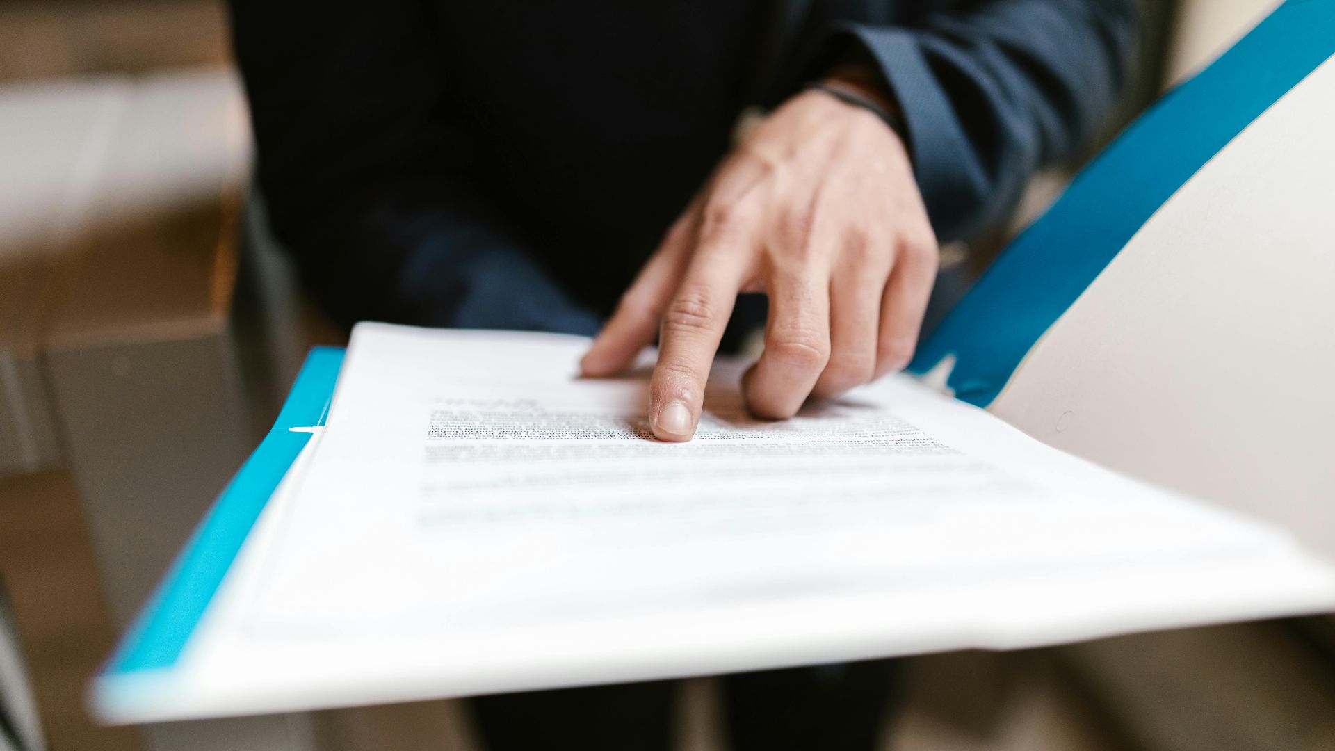 Close-up of a hand pointing at text on a business document in an office environment.