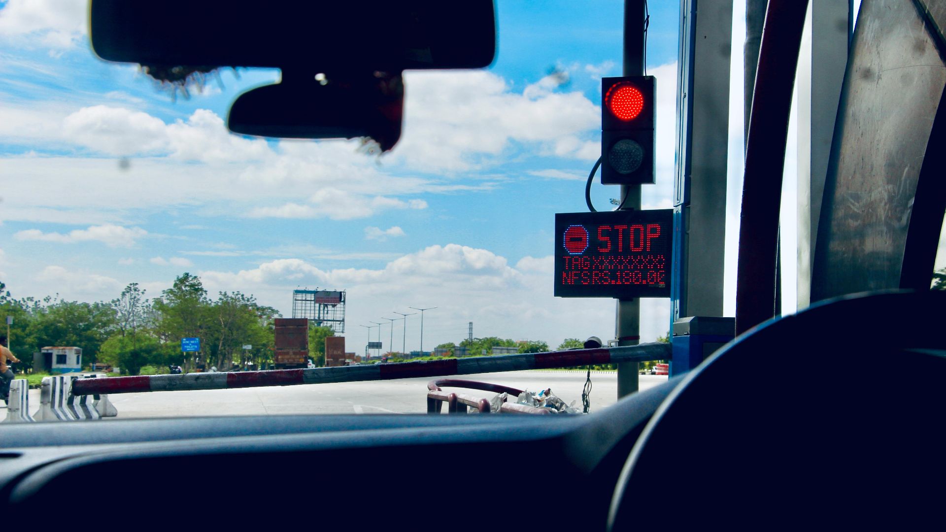 Car interior view at a toll booth in Suryapet, India with a stoplight.