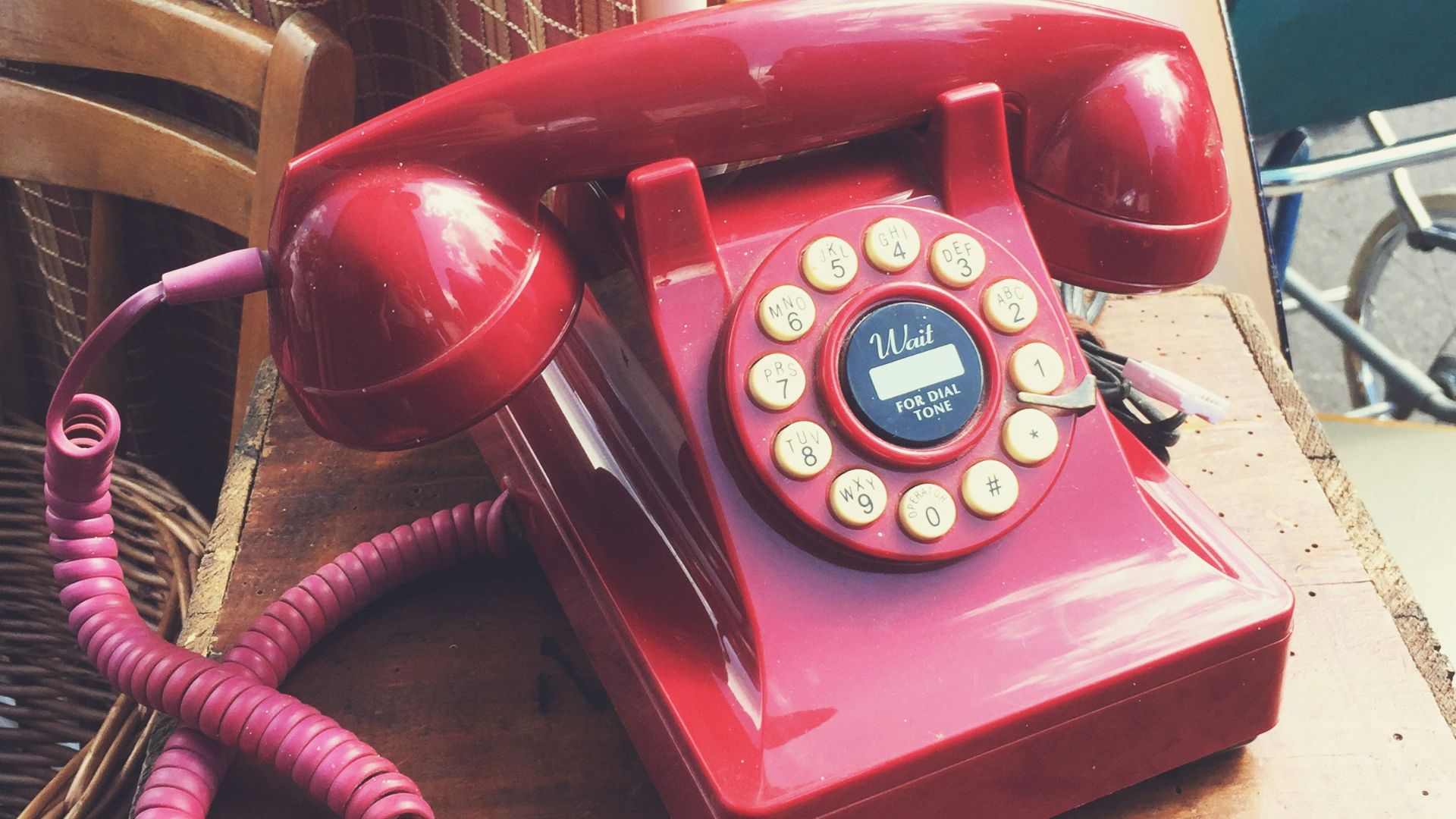A red telephone sitting on top of a wooden table