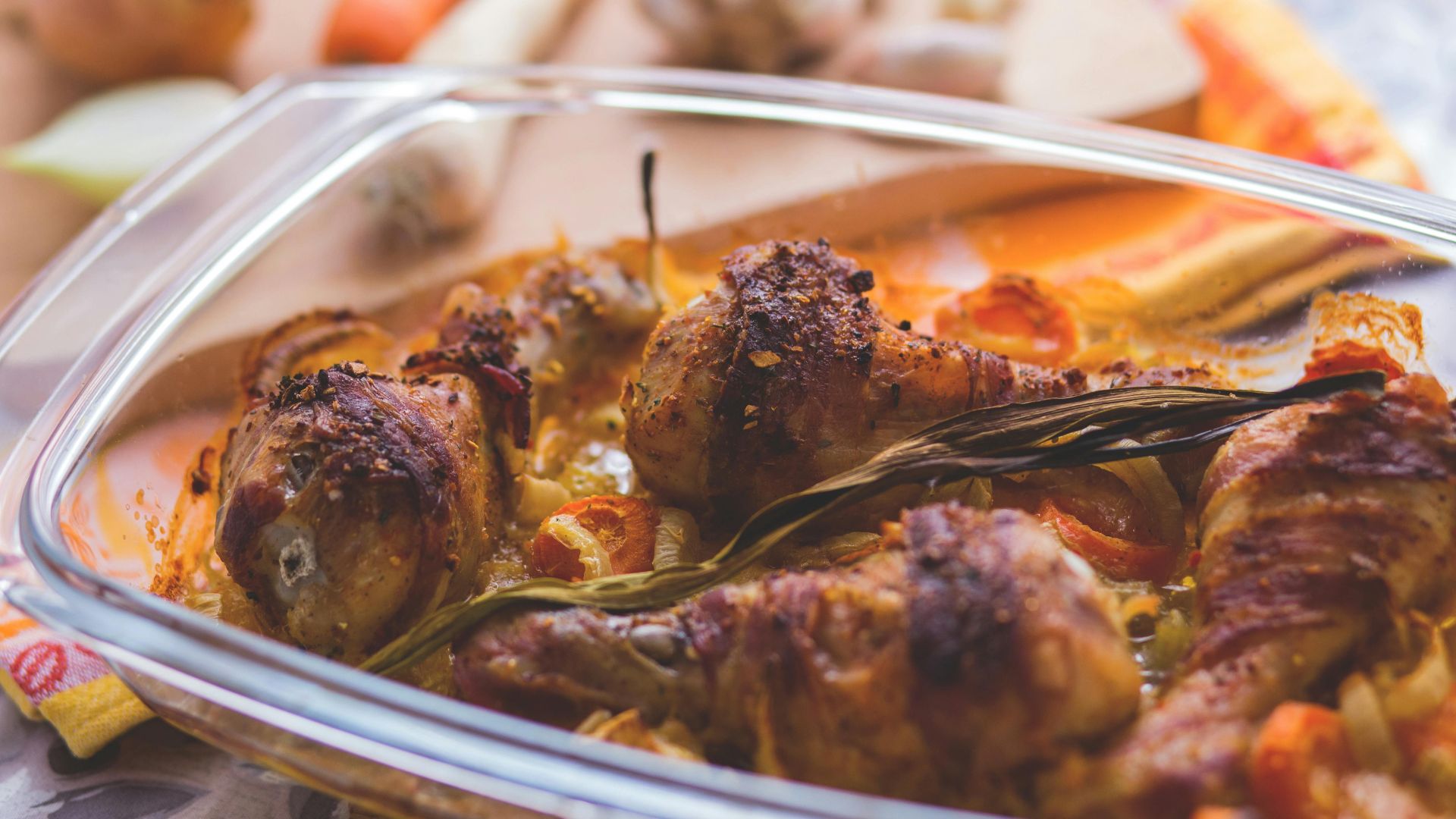 Delicious roasted chicken drumsticks with vegetables in a glass dish, perfect for a family meal.